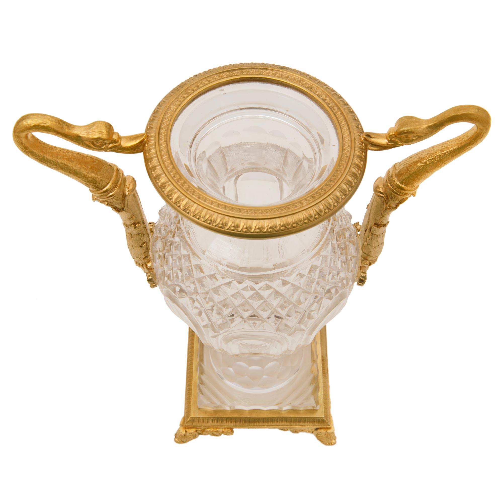 Paire de vases néo-classiques français du XIXe siècle en bronze doré et cristal de Baccarat. Chaque vase est surélevé par une élégante base carrée avec une bande enveloppante en bronze doré et des pieds en palmettes. Ces magnifiques vases en cristal