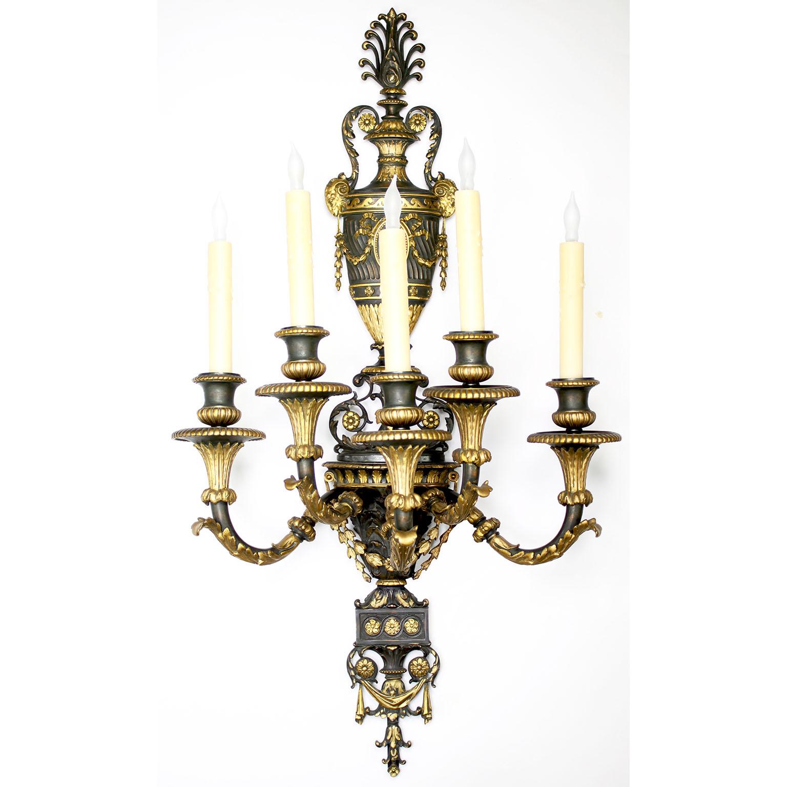 A very fine Pair of French, 19th Century Empire-Neoclassical style parcel-gilt and patinated bronze five-light wall lights (Sconces). The elongated dark patinated two-tone frames, each surmounted with a classical urn back-plate with floral wreaths