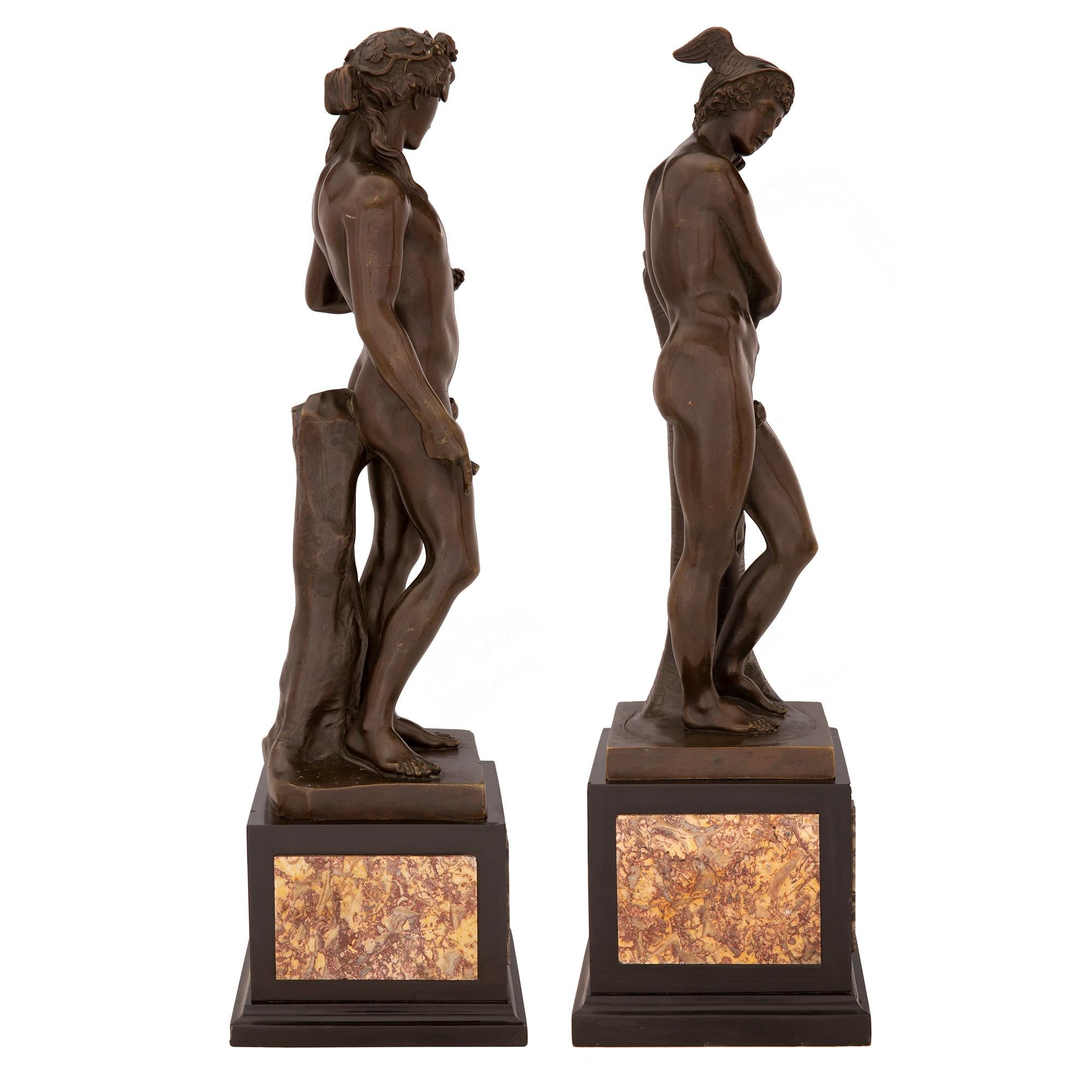 A striking pair of French 19th century Neo-Classical st. patinated bronze statues of Bacchus and Mercury. Each wonderfully executed statue is raised on a square base decorated with unique Blue Tourmaline gemstones on the front and Brocatelle