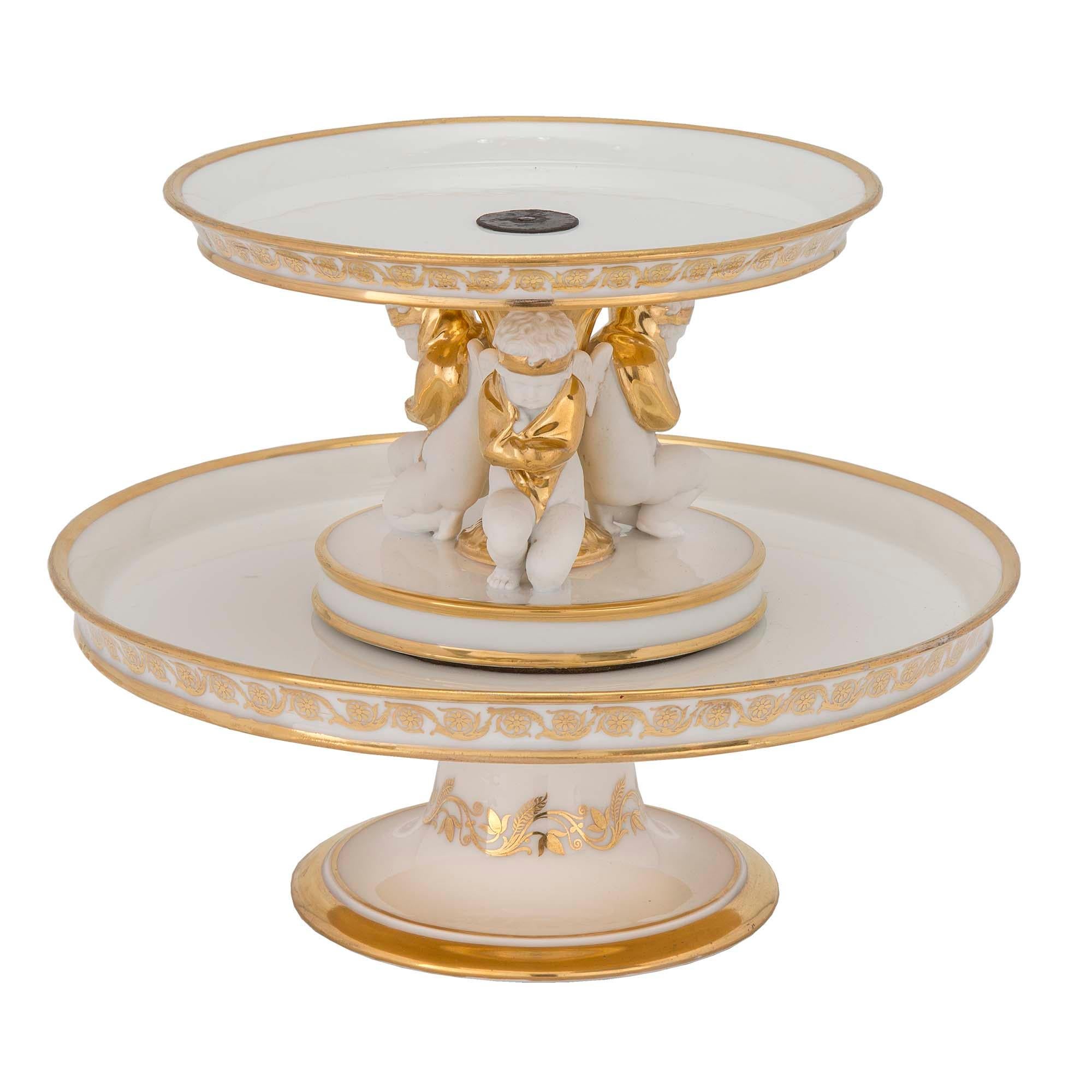 An extremely elegant pair of French 19th century neo-classical st. Porcelain de Paris and gilt, two tiered Presentoirs. Each is raised by a circular socle pedestal with a gilt band and fine foliate design. Each tier display wonderful gilt scrolled