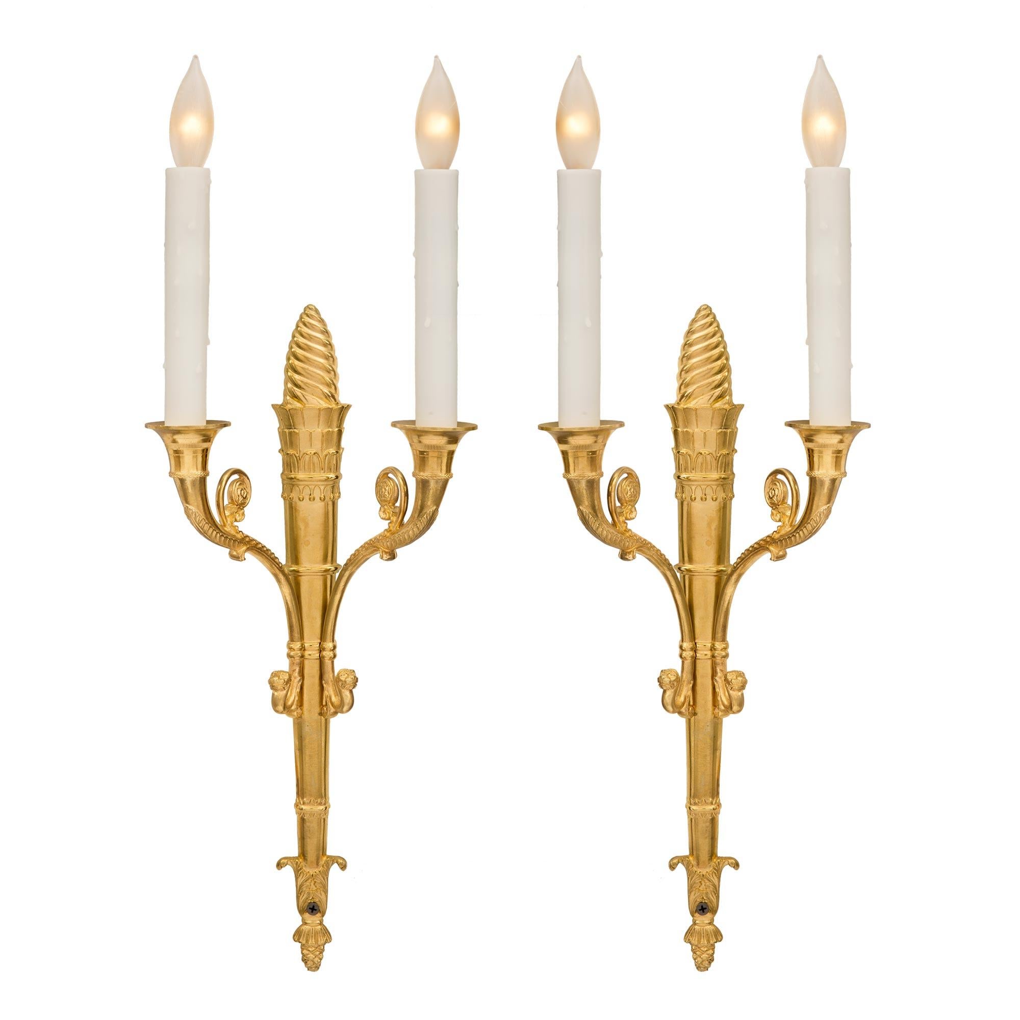 An elegant pair of French 19th century neoclassical two-arm ormolu sconces. Each sconce is centered by a fine bottom acorn finial adorned with acanthus leaves. The tapered central fut is in the shape of a quiver and displays a striking spiraled top