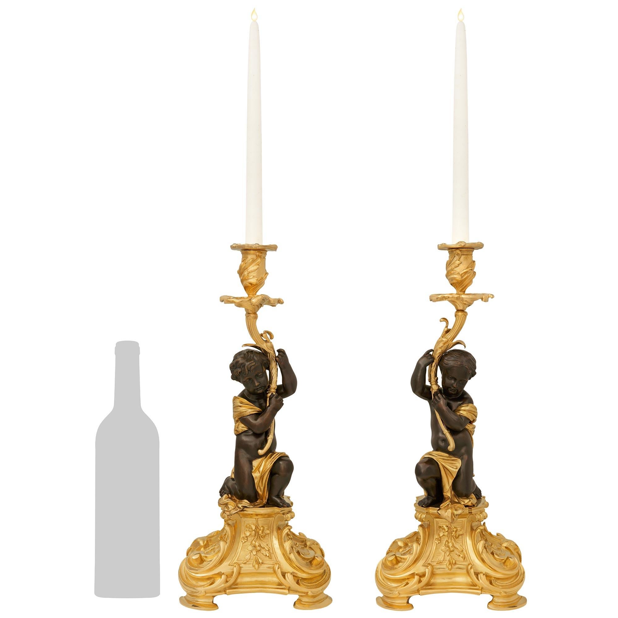An elegant and high quality pair of French 19th century Belle Epoque Period Ormolu and patinated Bronze candlesticks, signed Henri Picard. This impressive pair of candlesticks are raised on square Ormolu bases raised on scrolled feet and displaying