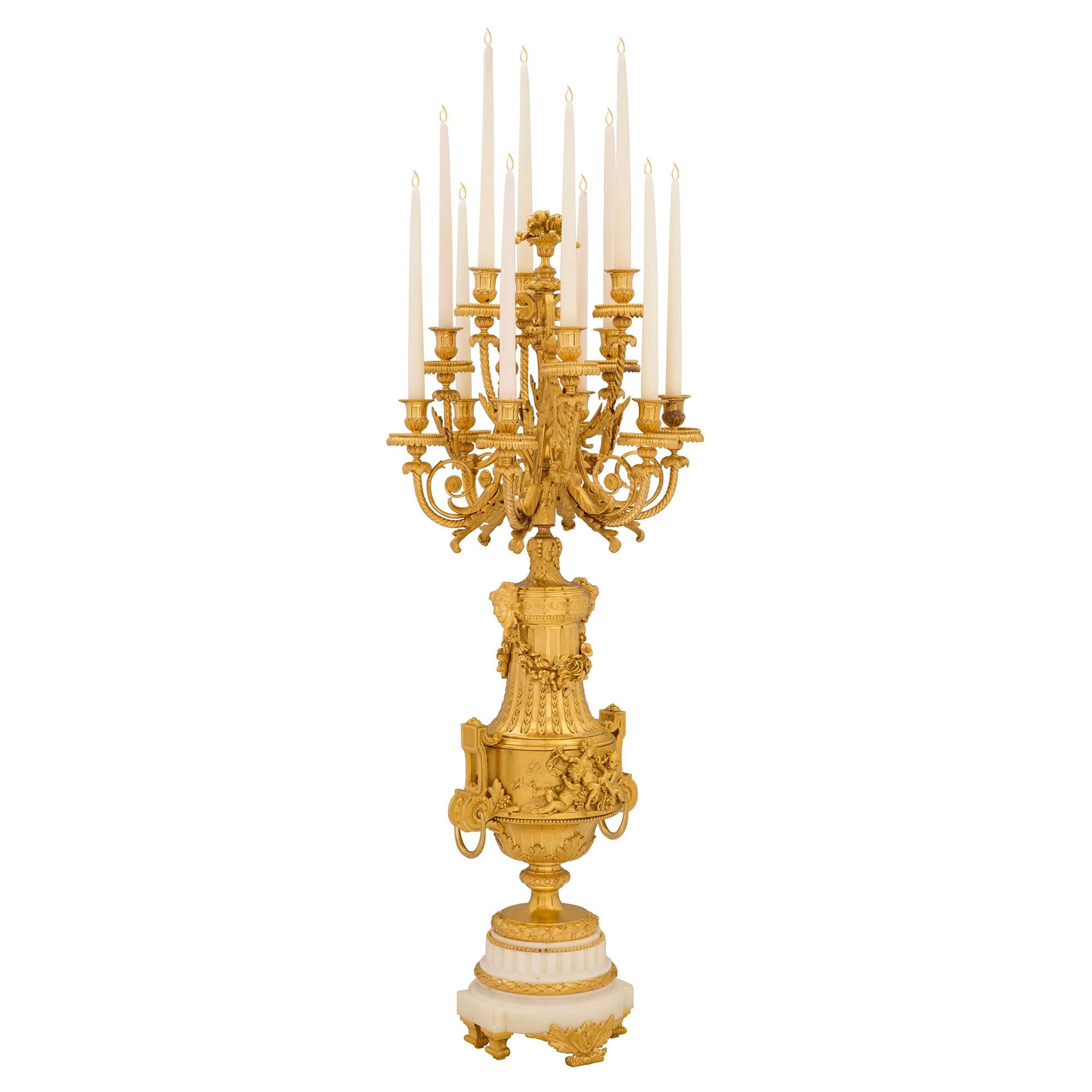 Une paire de candélabres en bronze doré et en marbre blanc de Carrare du 19ème siècle français de très haute qualité. Chaque candélabre de taille monumentale est surélevé par d'élégants pieds feuillus et un support en marbre blanc de Carrare. Les