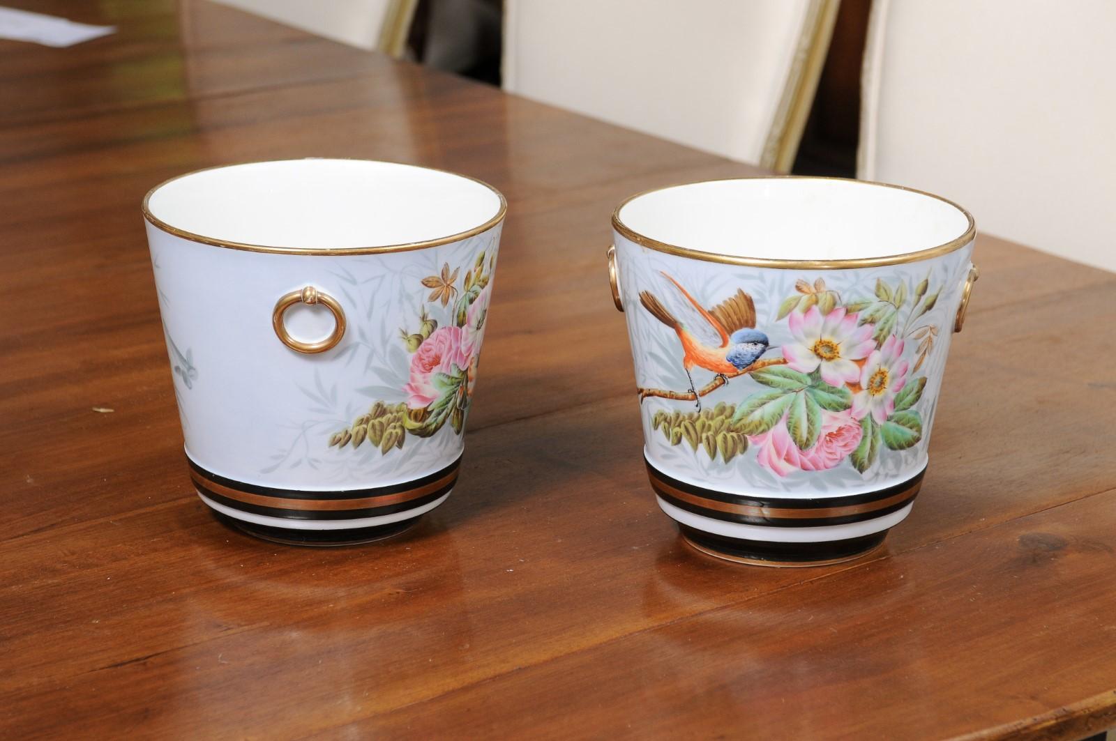 A pair of Porcelain de Paris cachepots planters from the 19th century, with hand-painted bird and floral motifs, and gilt accents. Created in France during the 19th century, each of this pair of cachepots features a circular tapering body, adorned