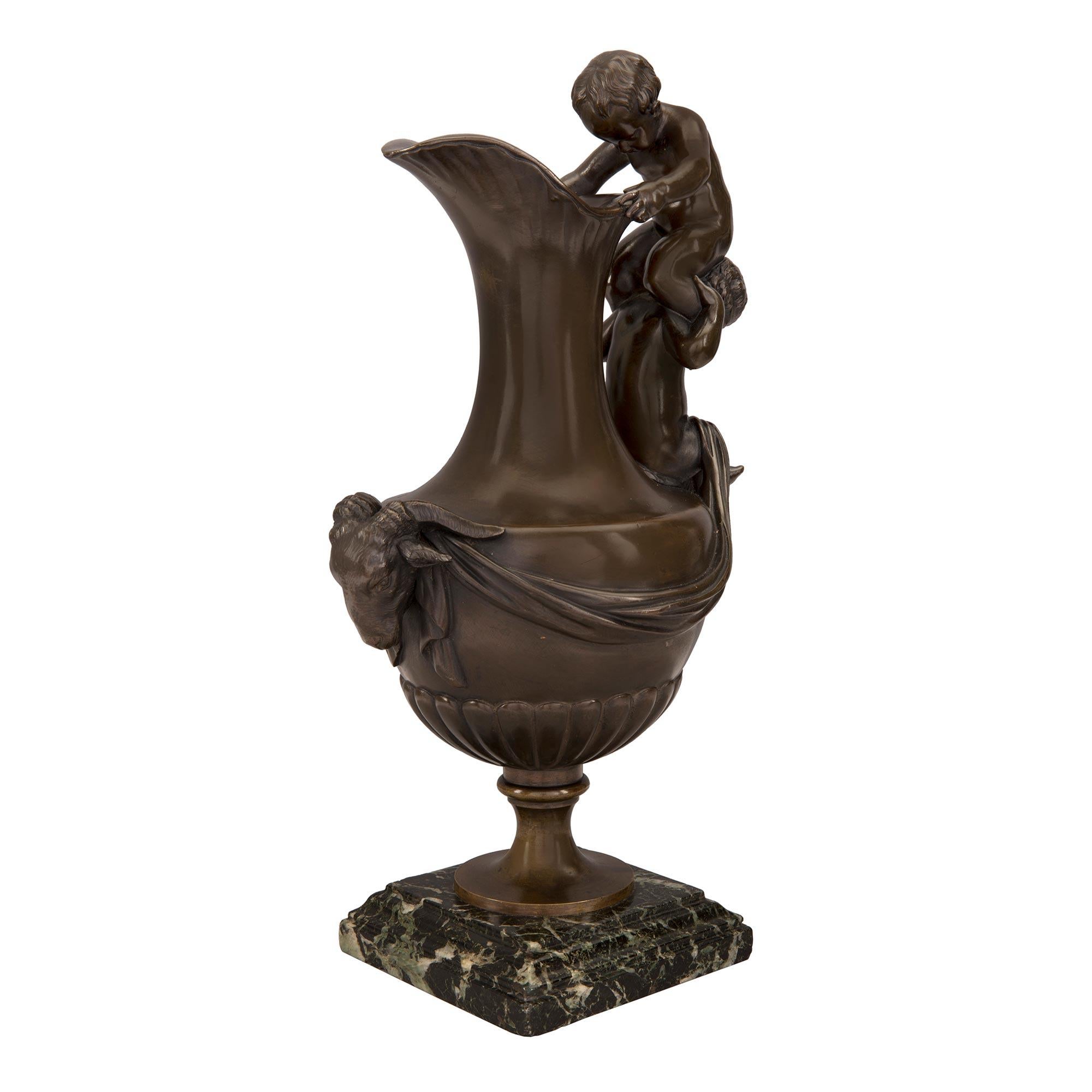 A wonderful and very decorative pair of French 19th century patinated bronze ewers. Each bronze ewer is raised by a Vert Maurin marble base with a mottled border. Above the socle pedestal is the elegantly shaped body with a reeded design and a