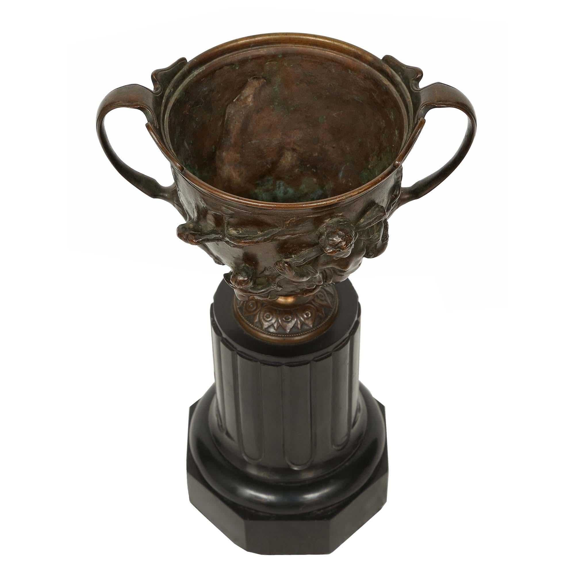 A very attractive pair of French 19th century patinated bronze tazzas which are raised by a high reeded column black Belgian marble base with an octagonal shaped plinth. Above the base is a circular support with a water leaf design. The tazzas are