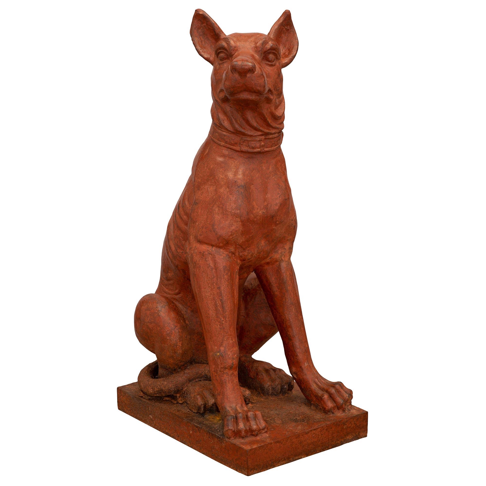 A handsome and most impressive true pair of French 19th century patinated cast iron dog statues. Each statue is raised by a rectangular base where the dogs above are seated while wearing a collar with fine detail throughout. All original terra cotta