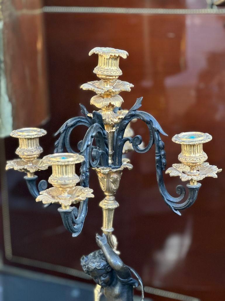 Pair of antique bronze and marble putti candelabras made in France in the 19th Century. Each candelabra has five candle holders. Each marble base is finely detailed with gilt bronze figures and is supported by bun feet.
Dimensions:
23.5