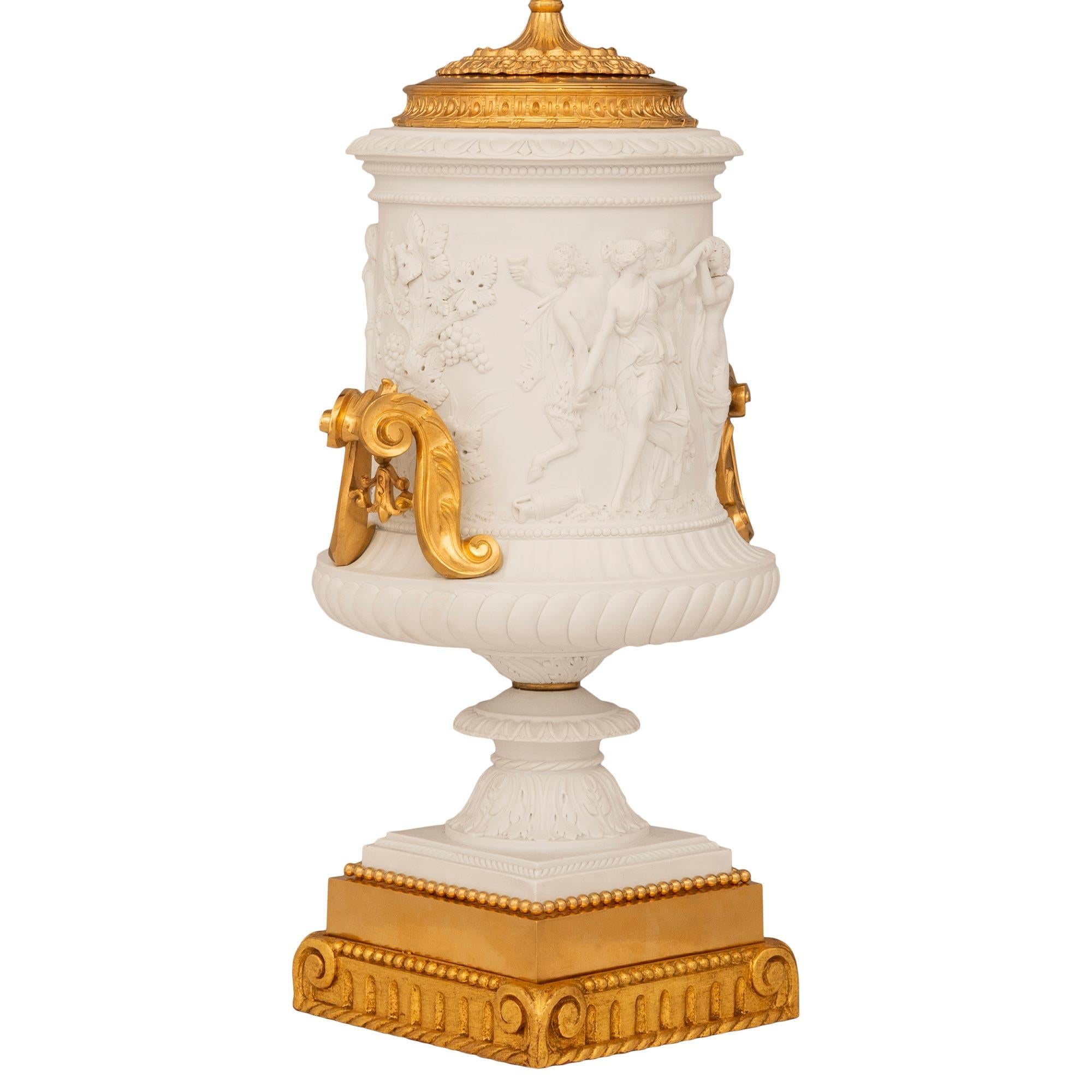 Superbe paire de lampes Renaissance en porcelaine biscuitée, bronze doré et bois doré, attribuée à Sèvres, datant du XIXe siècle. Chaque magnifique lampe est posée sur un piédestal carré cannelé en bois doré, avec un bord inférieur en spirale et des