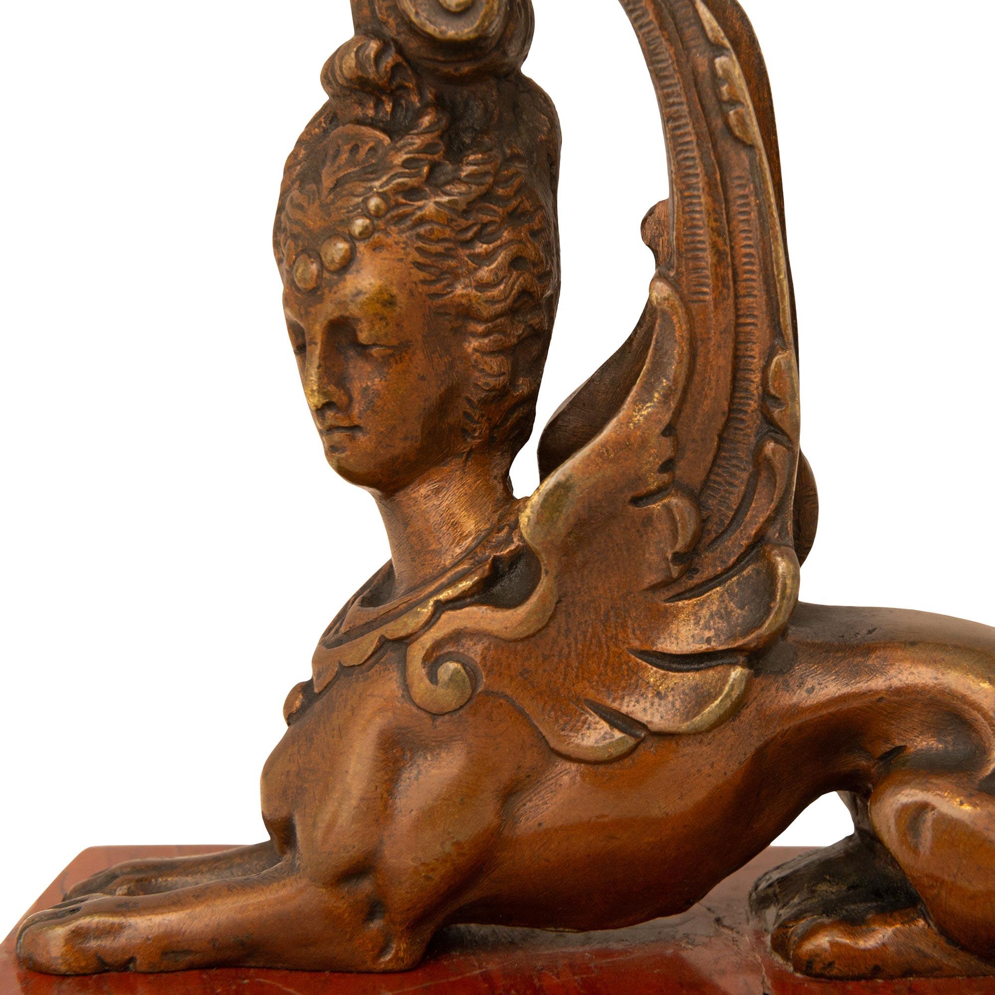 Ein hübsches Paar französischer Sphinx-Kerzenhalter aus Bronze und Rosso Antico-Marmor aus dem 19. Jeder Sphinx-Kerzenhalter aus Bronze im ägyptischen Revival wird von einem rechteckigen Sockel aus Rosso-Antico-Marmor getragen. Dieses Paar, das als