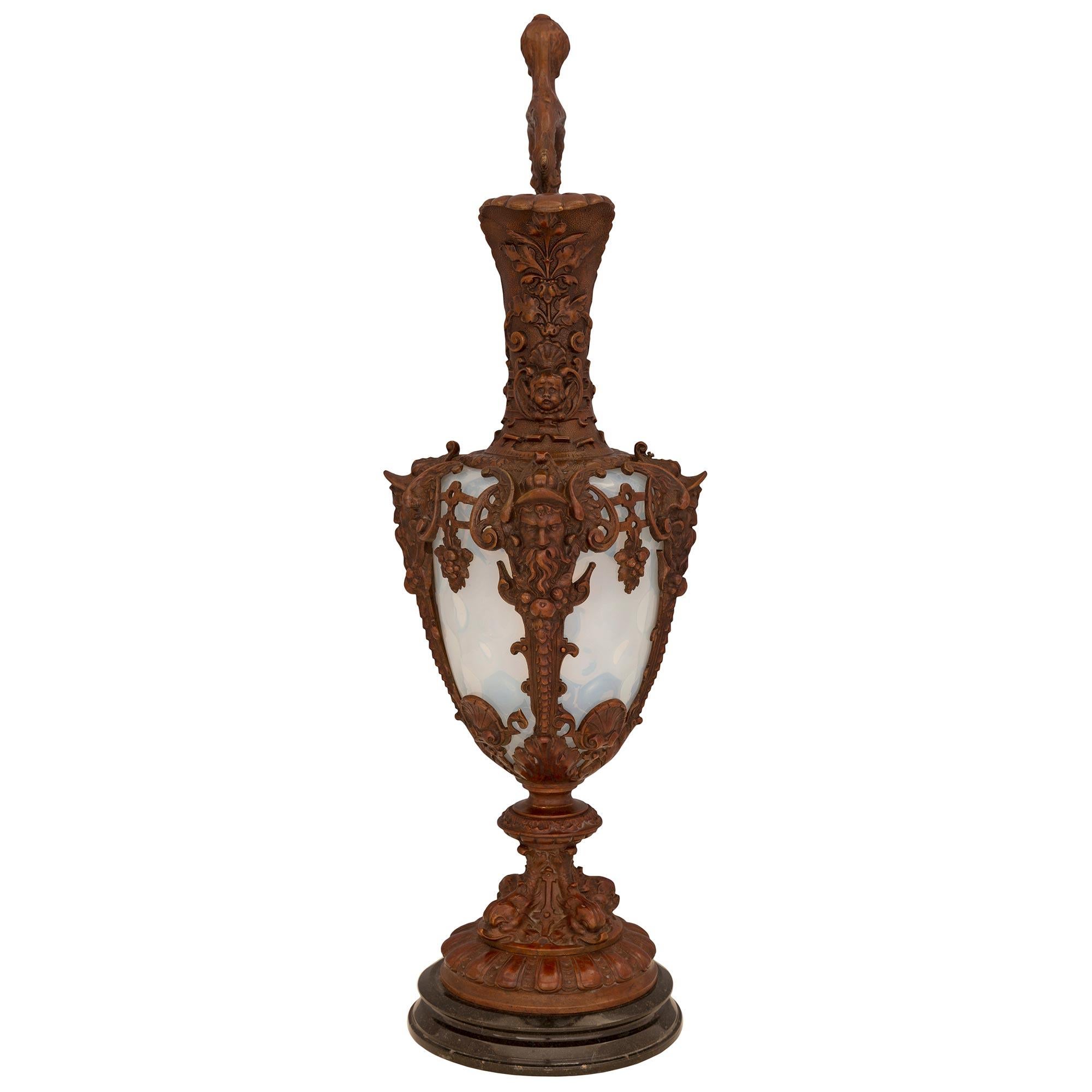 A striking and extremely decorative pair of French 19th century Renaissance st. patinated bronze, Opaline, and black Belgian marble ewers/urns. Each urn is raised by an elegant circular black Belgian marble base with a fine wrap around double