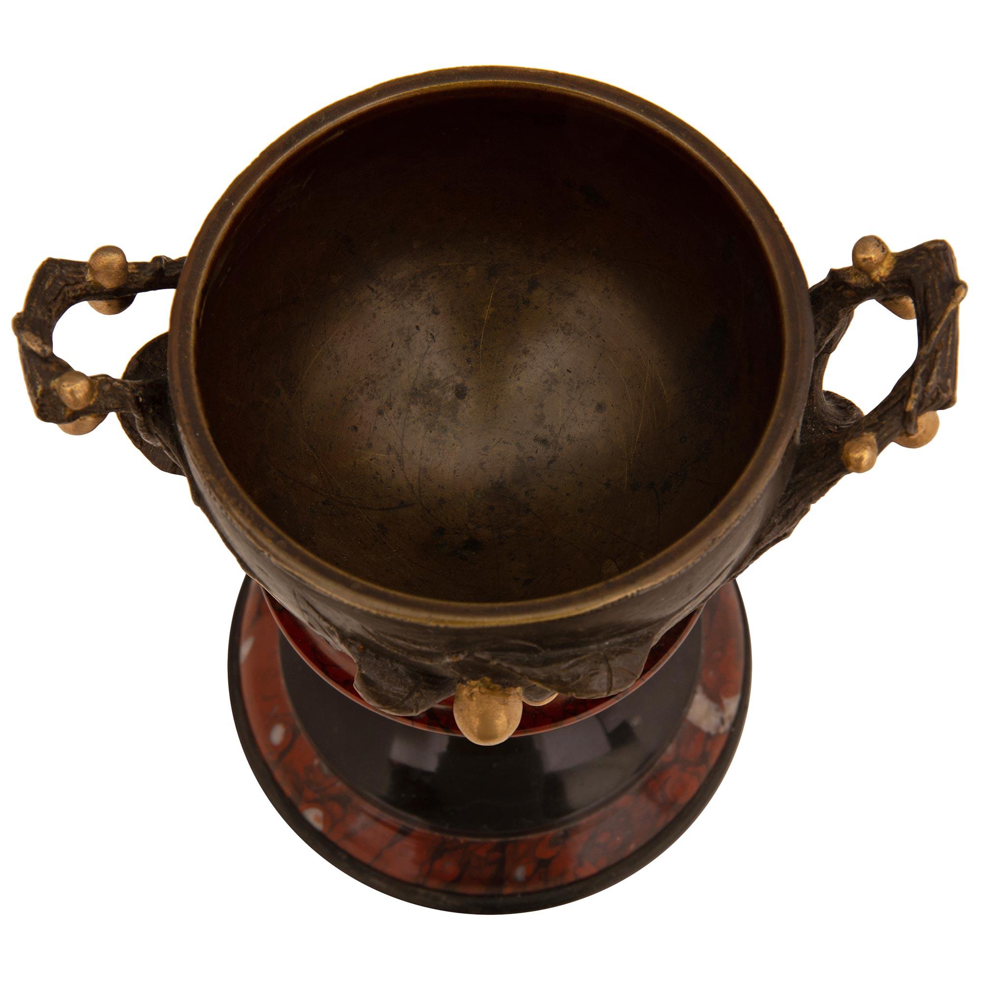 A fine pair of French 19th century Renaissance st. patinated bronze, ormolu Rouge Griotte, and Black Belgian marble tazzas. Each tazza is raised by a circular black Belgian marble base with a wrap around Rouge Griotte marble band. Above the elegant,