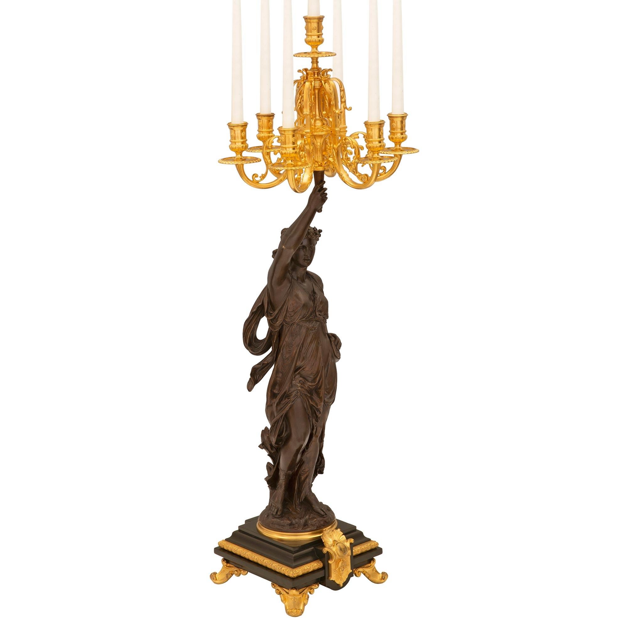 An impressive and high quality true pair of French 19th century Renaissance st. patinated bronze, ormolu, and black Belgian marble candelabras signed Grêgoire. Each seven arm candelabra is raised by elegant scrolled ormolu feet below the striking