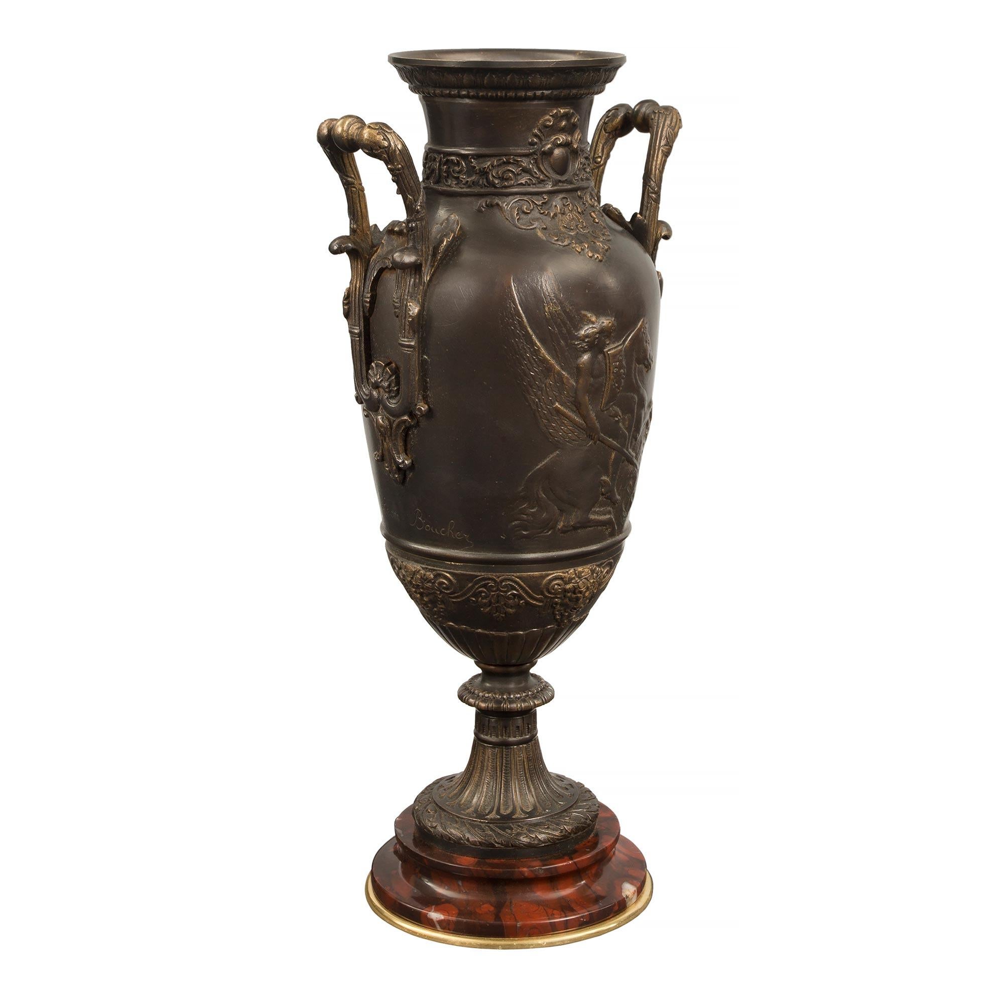A handsome pair of French 19th century Renaissance st. patinated bronze, ormolu and Rouge Griotte marble urns, signed Leon Boucher. Each urn is raised by a circular mottled Rouge Griotte marble base with a fine ormolu bottom band. The socle