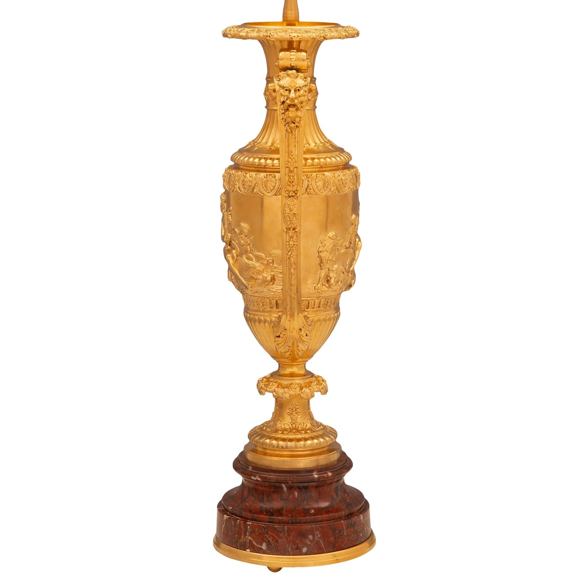A stunning and large scale true pair of French 19th century Renaissance st. ormolu and Rouge Griotte marble lamps. Each lamp is raised by a circular Rouge Griotte marble base with a mottled border and fine bottom ormolu band with fine ball feet. The