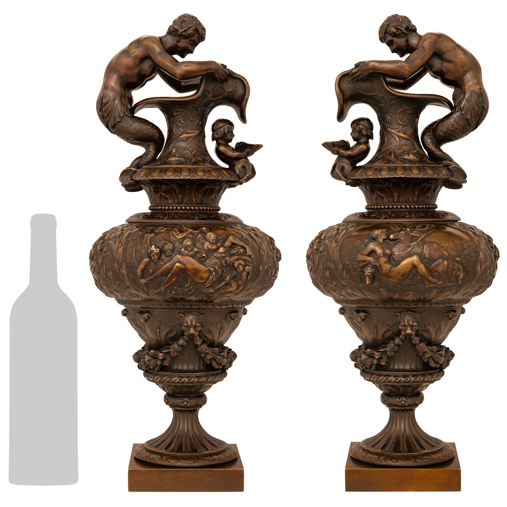 A stunning and most handsome pair of French 19th century Renaissance st. patinated Bronze ewers/urns. Each ewer is raised by a square base below a fluted socle decorated with a foliate band at the center and spiral band above. The body of each ewer