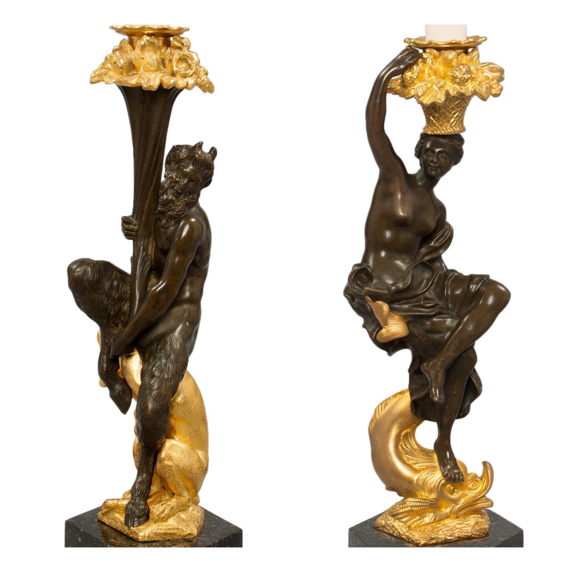 Une paire exceptionnelle de chandeliers français du 19ème siècle de style Renaissance en bronze patiné, bronze doré et granit belge. Chaque chandelier est surélevé par des bases hexagonales en granit avec une bande inférieure enveloppante en bronze
