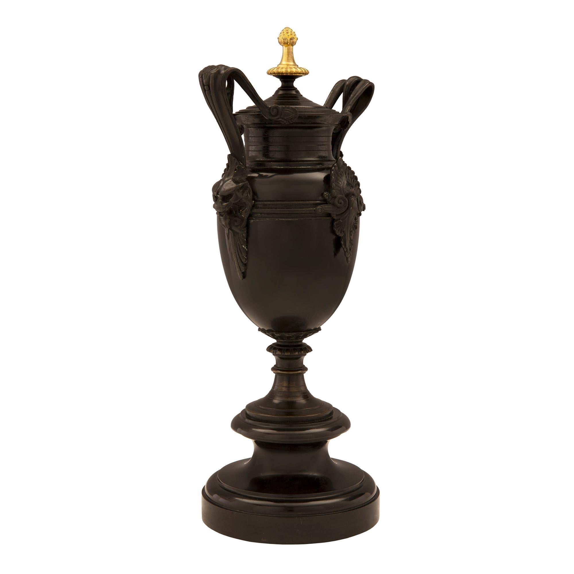 A handsome pair of French 19th century Renaissance st. patinated bronze and ormolu urns. Each urn is raised by a circular base with a mottled border below the socle shaped support. The body displays an impressive central palmette amidst scrolled
