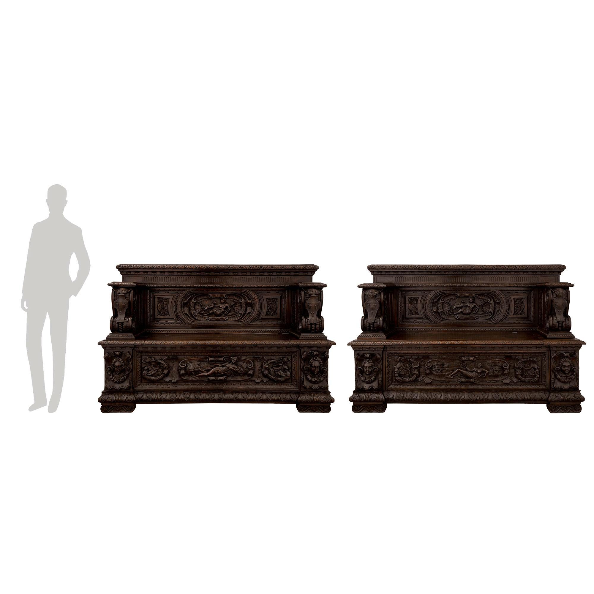 An extremely handsome and most impressive pair of French 19th century Renaissance st. patinated dark oak benches, circa 1870. Each bench is raised by fine scrolled feet below the straight frieze with a superb carved foliate band. At the center of