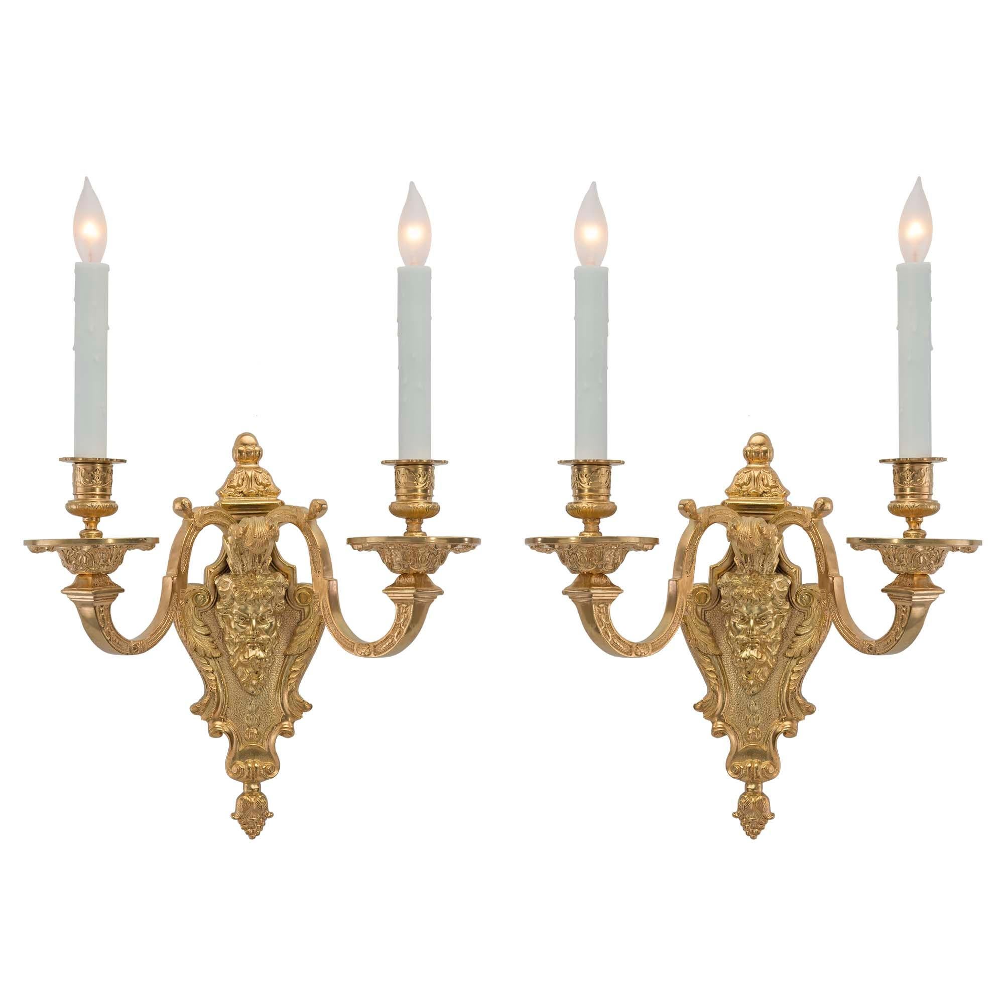 An elegant pair of French 19th century Renaissance two arm ormolu sconces. Each sconce is centered by a finely chased bottom acorn finial. At the center is a handsome and detailed bearded man on a hammered background with scrolled acanthus leaves