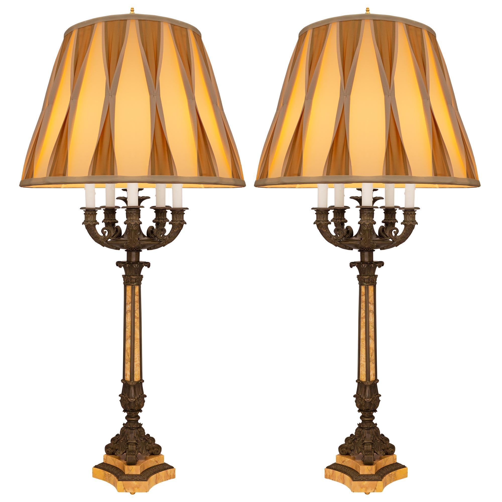 A sensational and large-scale pair of French 19th century Restauration period seven light patinated bronze and marble candelabra lamps. Each five-arm candelabras is raised on a triangular sienna marble base with concave sides and cut corners below a