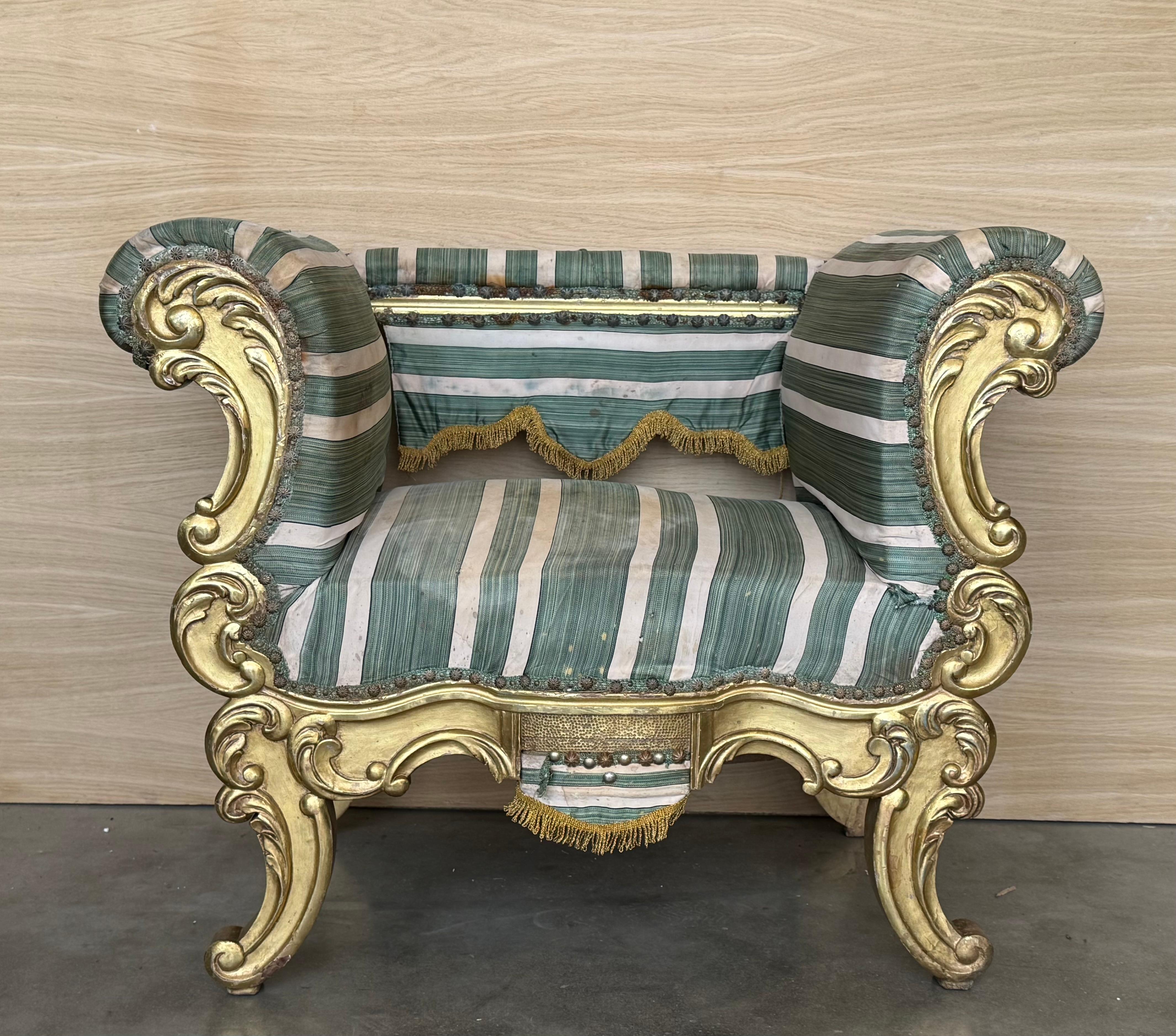 An exquisite French 19th century giltwood armchair. This one-of-a-kind piece has every curve of the carved wood frame complemented beautifully by the warm gilt finish and striking distressed fabric. In very good vintage condition, this classic
