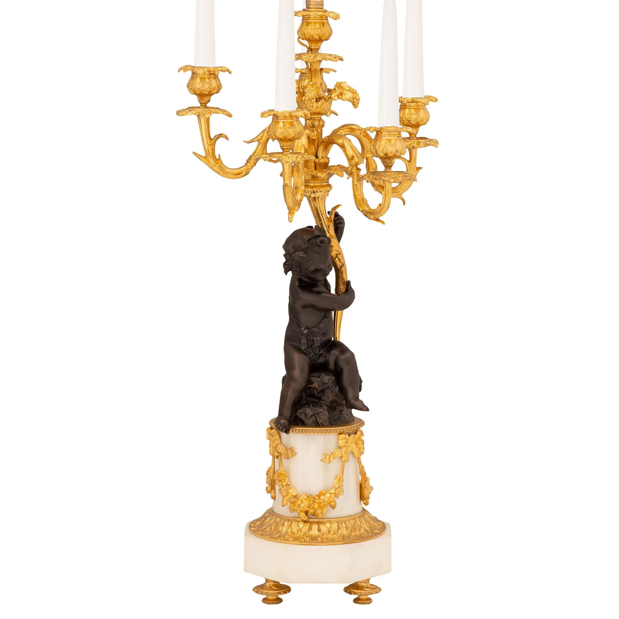A stunning and high quality pair of French 19th century white Carrara marble, ormolu and patinated bronze candelabra lamps. Each six arm candelabra is raised by fine ormolu topie feet below the octagonal white Carrara marble base with a fine wrap