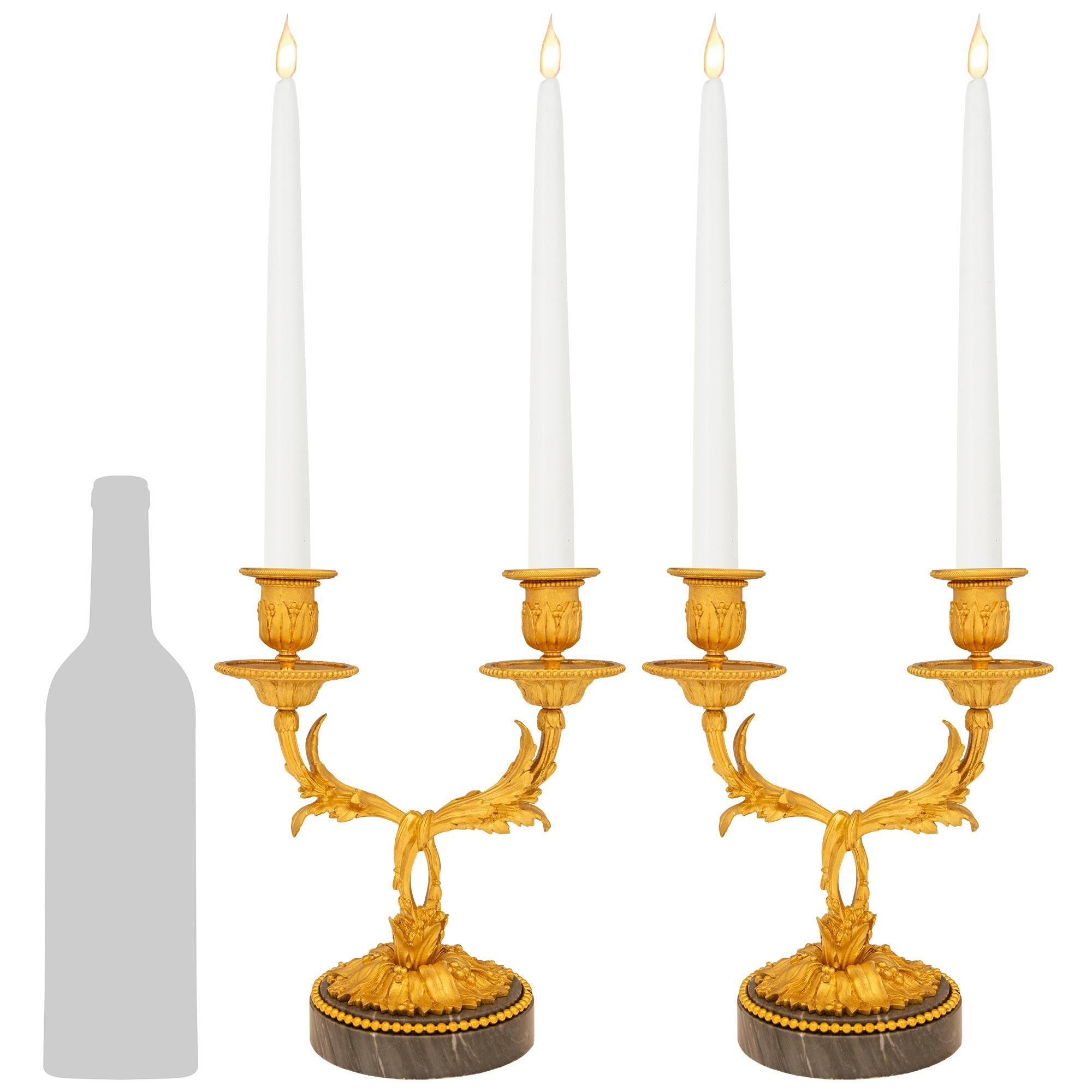 Una coppia elegante e di alta qualità di candelabri francesi del XIX secolo in marmo Bleu Turquin e Ormolu. Ogni splendido candelabro a due bracci è sollevato da una base circolare in marmo Bleu Turquin decorata con una fascia di perline in Ormolu.