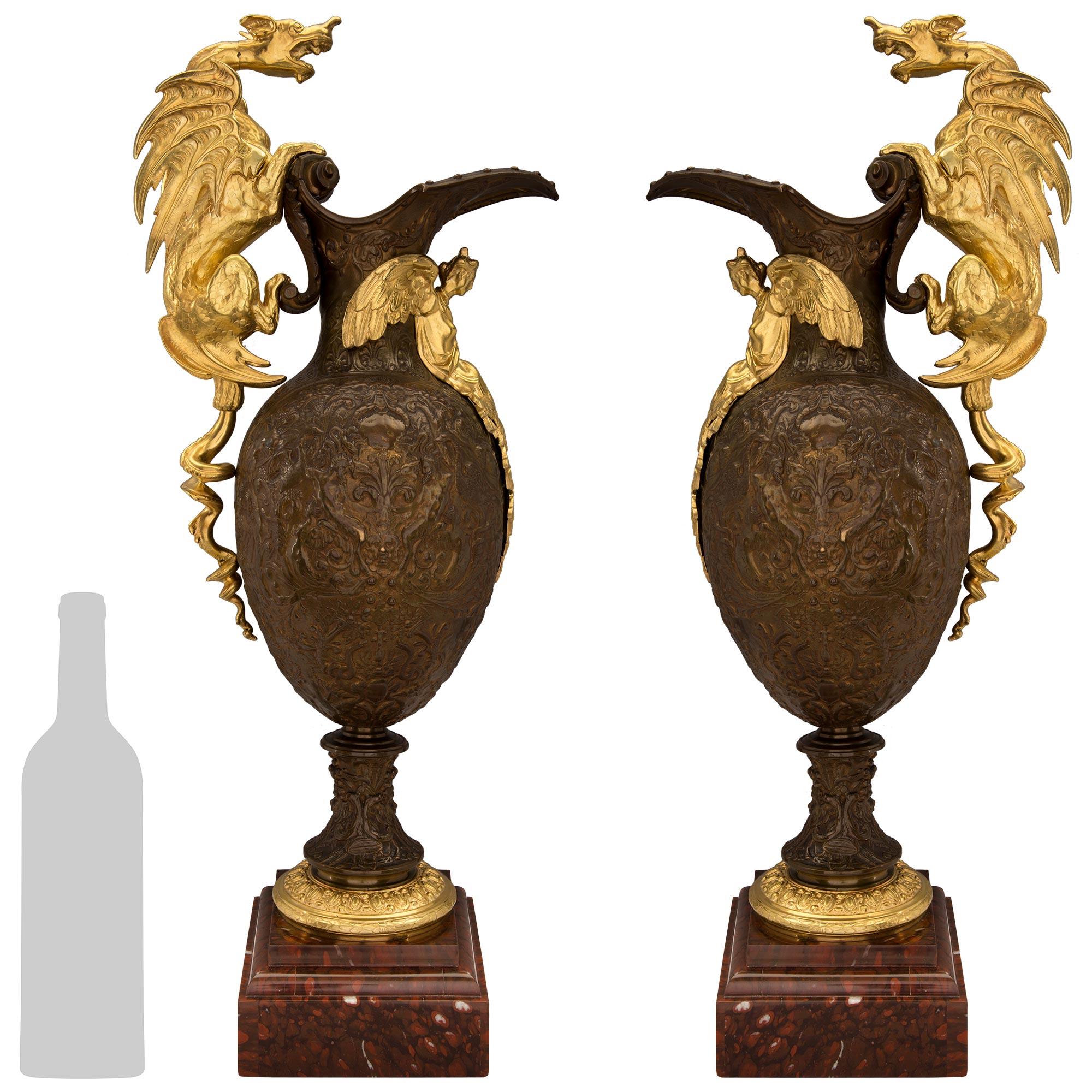 A stunning and most unique pair of French 19th Renaissance st. Ormolu, patinated Bronze and Rouge Griotte Marble ewers. Each stunning urn is raised by a square Rouge Griotte Marble base with mottled stepped borders. The socle pedestals display fine
