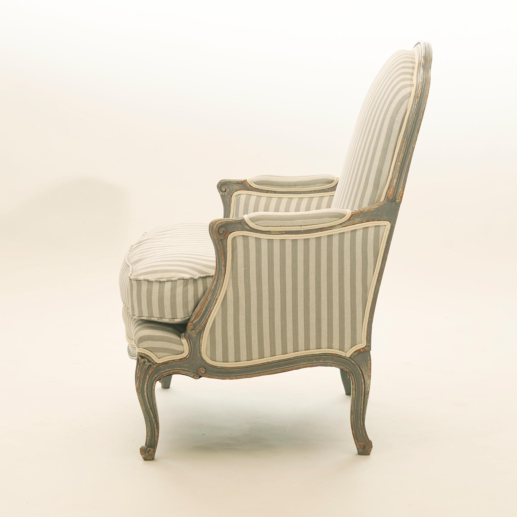 Pair of French easy chair / bergère chairs. Rococo style. Gray painted with a beautiful patina. Upholstered in new fabric in gray shades. France, circa 1920. Sold as a pair.
