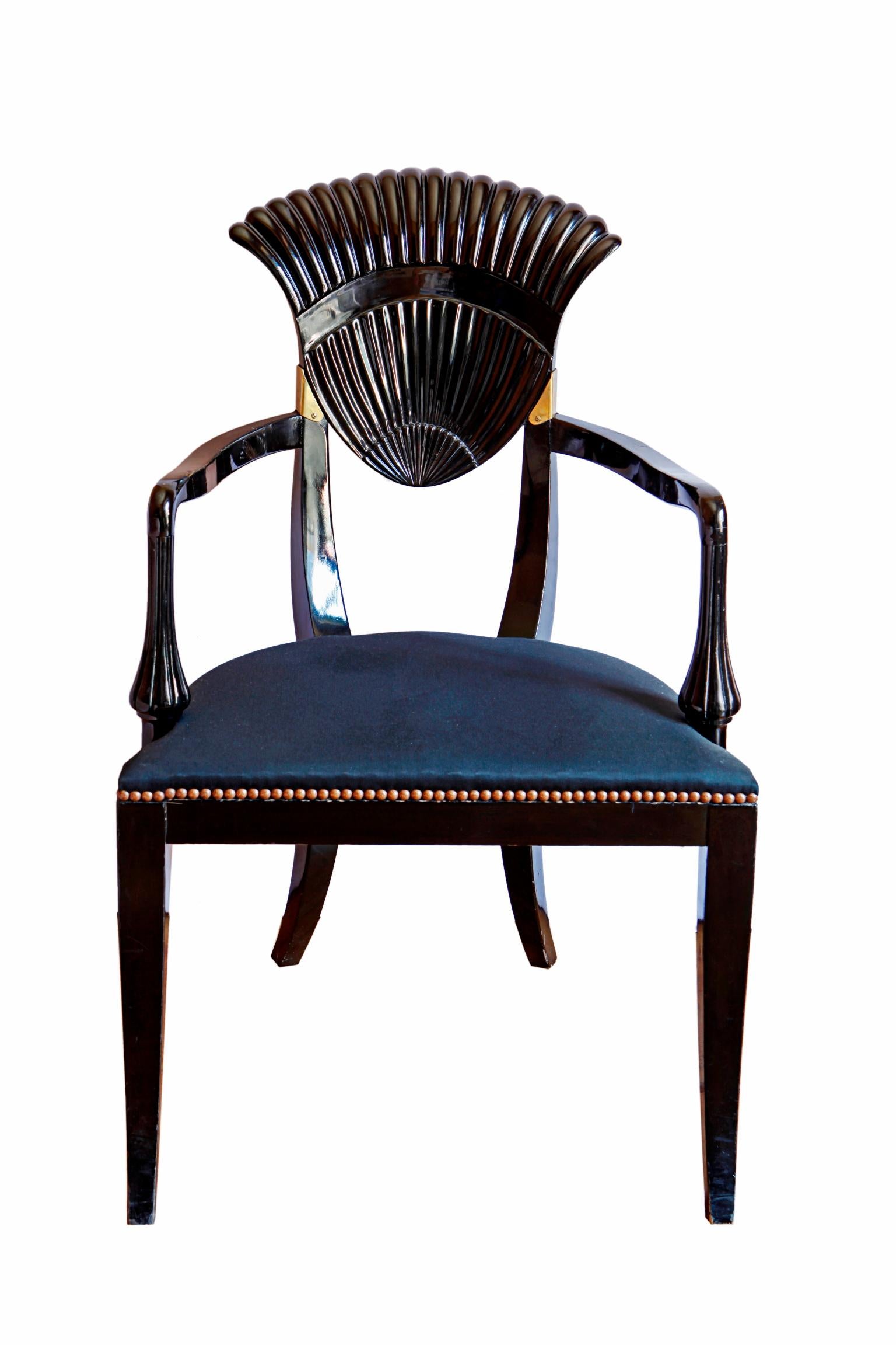 Pair of black lacquered armchairs with a brass detail in the back. Fan shaped back and serpentine shaped armrests above a black padded seat. On sabre legs.