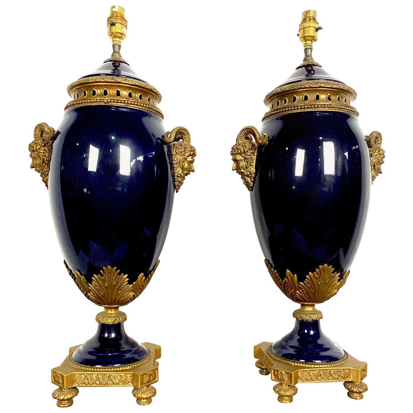 Elegantísima pareja de lámparas francesas del siglo XX, estilo Luis XVI, de porcelana azul cobalto de Sèvres y ormolu. Cada lámpara se eleva sobre una base de ormolu con bordes de cuentas. El cuerpo de porcelana de estilo Sèvres, en forma de
