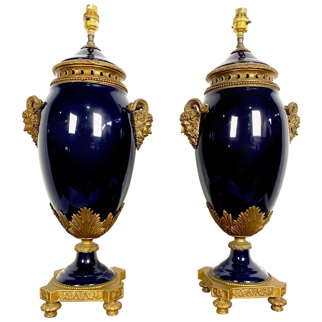 Une très élégante paire de lampes de style Louis XVI du 20e siècle en porcelaine de Sèvres bleu cobalt et bronze doré. Chaque lampe repose sur une base en bronze doré avec des bordures perlées. Le corps de forme balustre en porcelaine de style