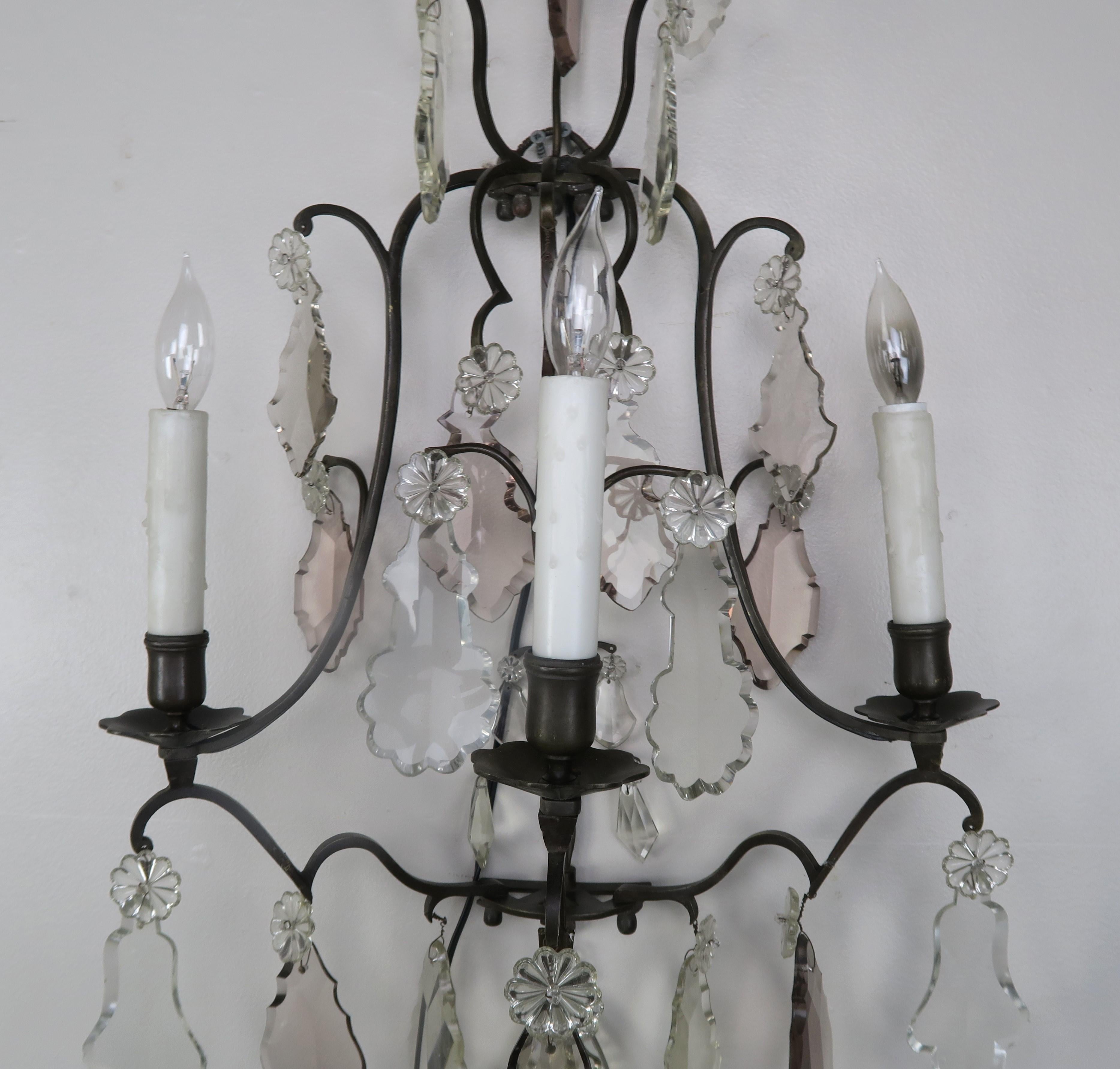 Pair of 3-light metal sconces adorned with large elegant shaped crystals throughout. The sconces are newly rewired with cream wax candle covers.
 