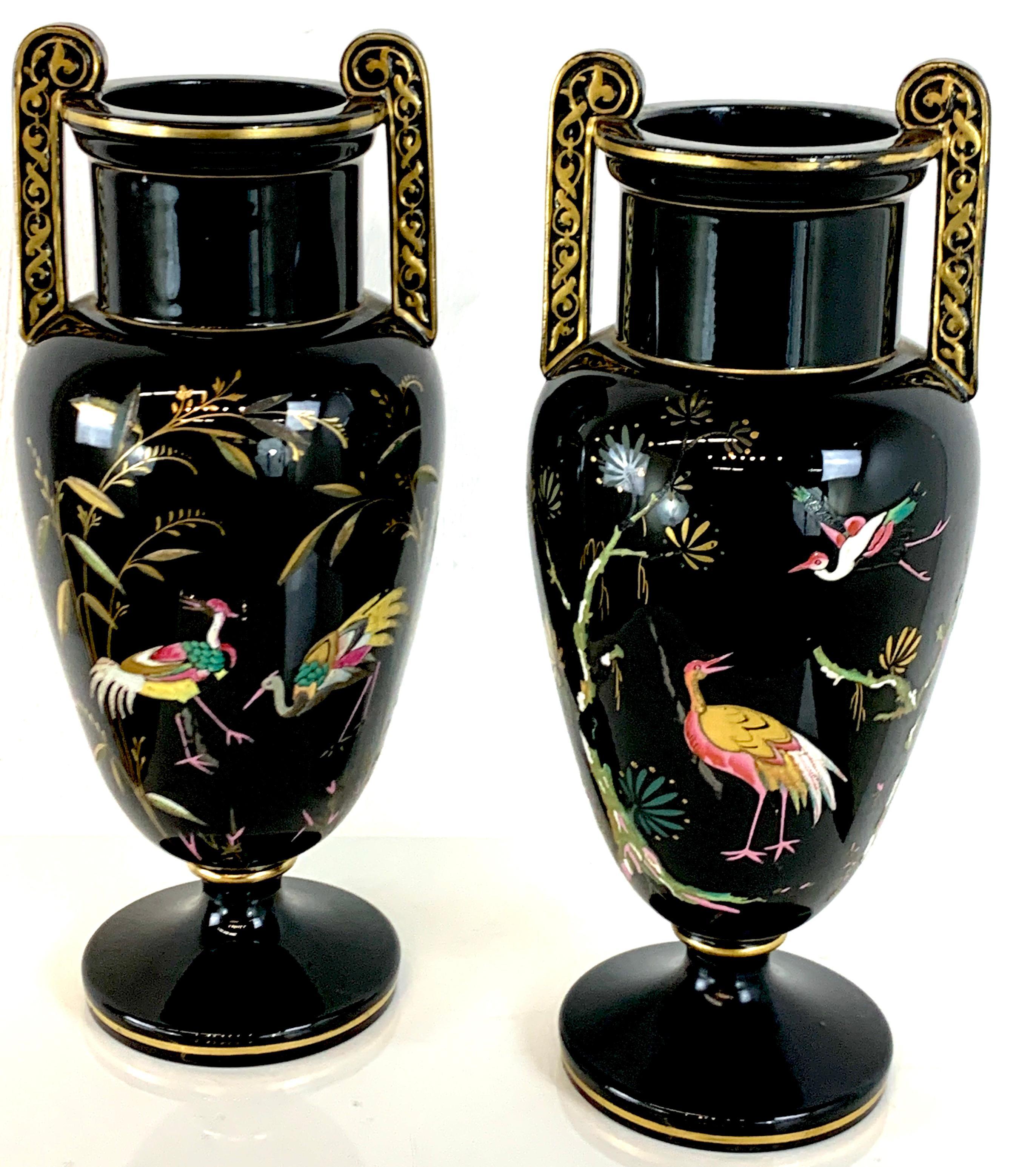 Pair of French Aesthetic movement enameled bird motif black & gold vases, each one with twin applied handles, colorful decoration on both sides, raised on a 4