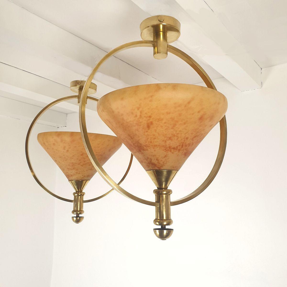 Coppia di lampadari a sospensione della metà del secolo scorso, Francia 1960.
Le luci vintage sono realizzate in vetro ambrato traslucido e montature in ottone.
La coppia di fari ha una luce ciascuno, ricablata professionalmente per gli Stati