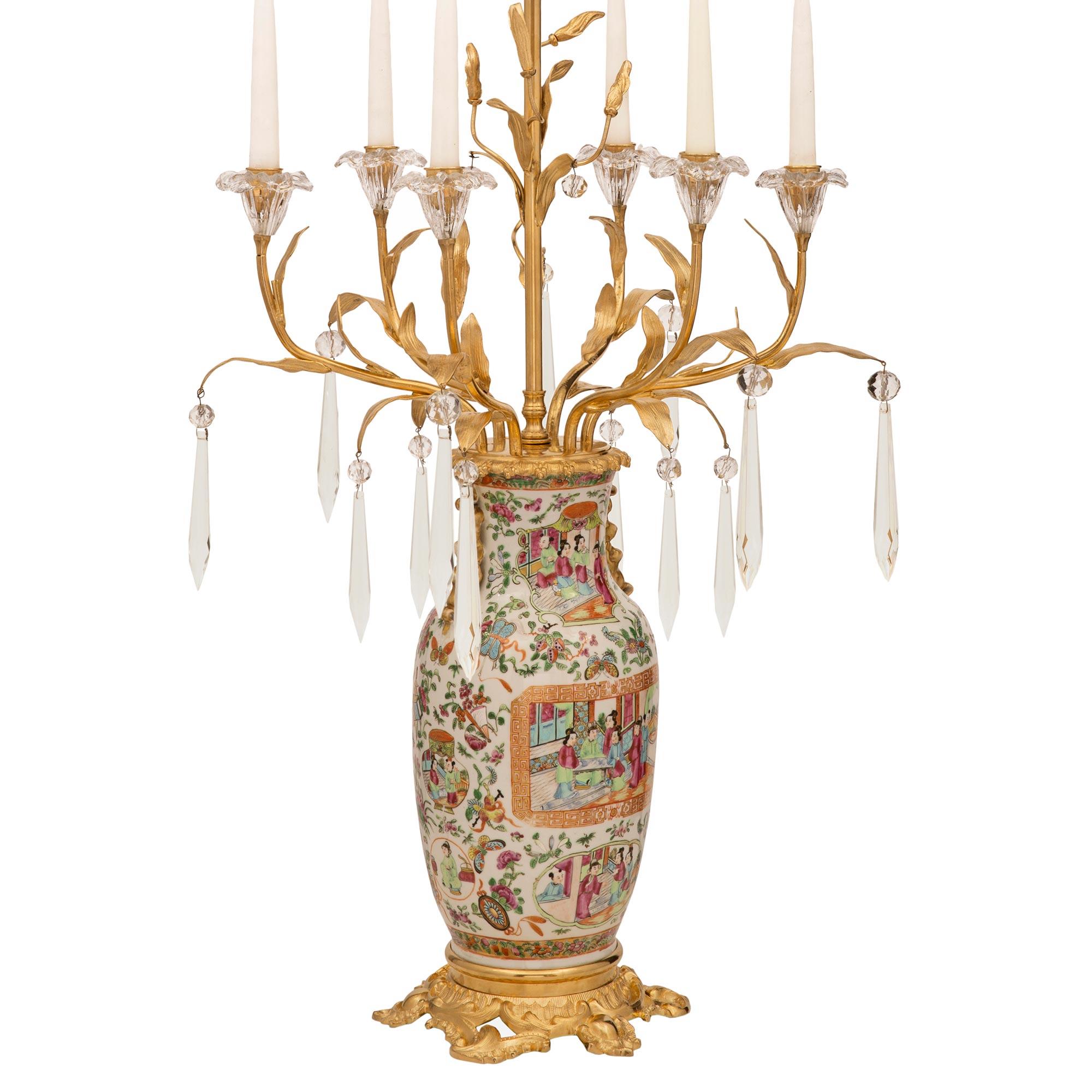 An impressive and extremely decorative pair of French and Asian collaboration 19th century Louis XV st. Famille Rose porcelain, crystal, and ormolu lamps. Each lamp is raised by an elegant and richly chased pieced ormolu base with beautiful scrolled