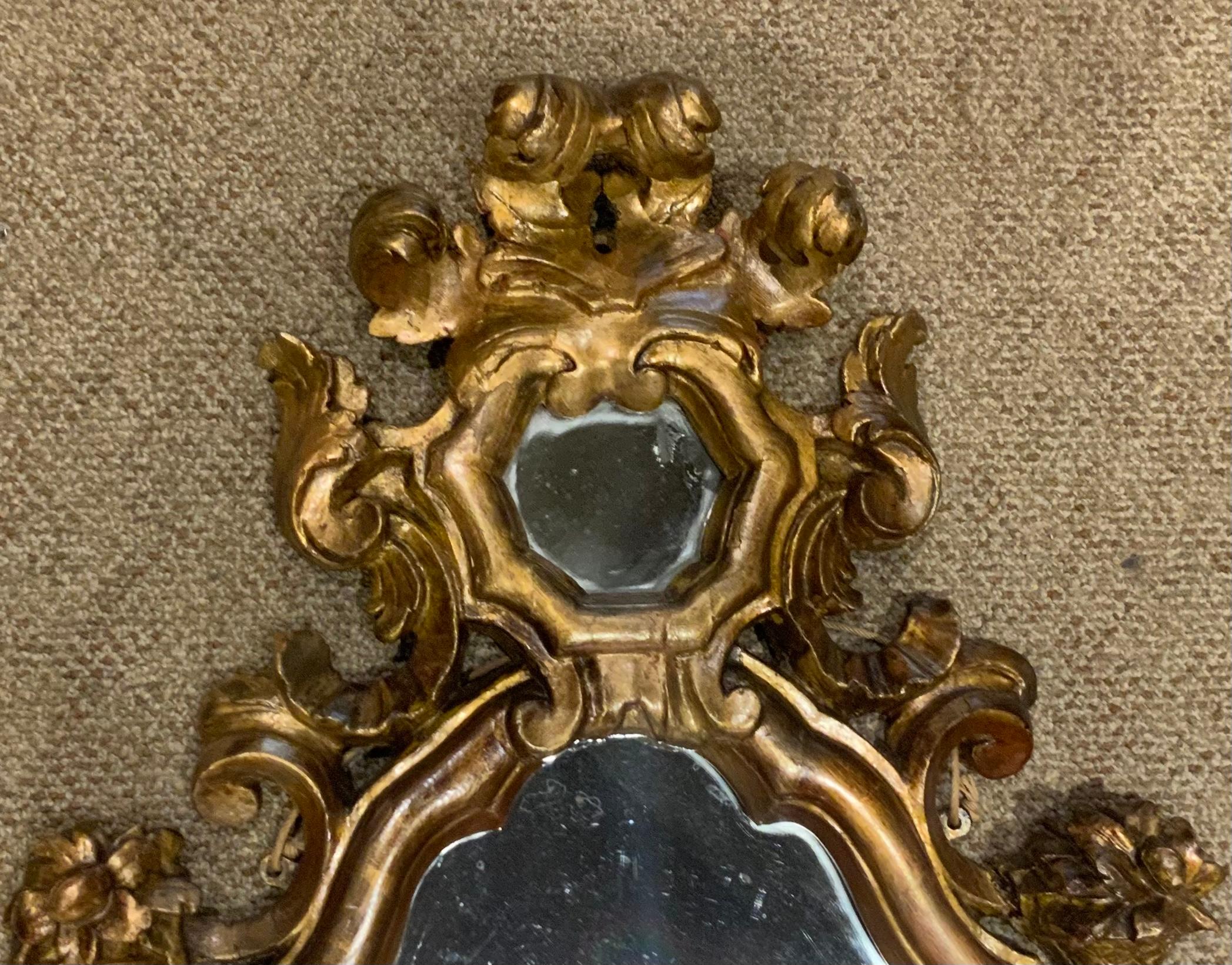 This pair is carved with floral motifs at the upper corners. The gilt
Wood has an aged patina in a soft gilt hue. The shaping is elongated
And the carving is exquisite with scrolls and flourishes throughout 
The mirror plate has no flaws or spots.