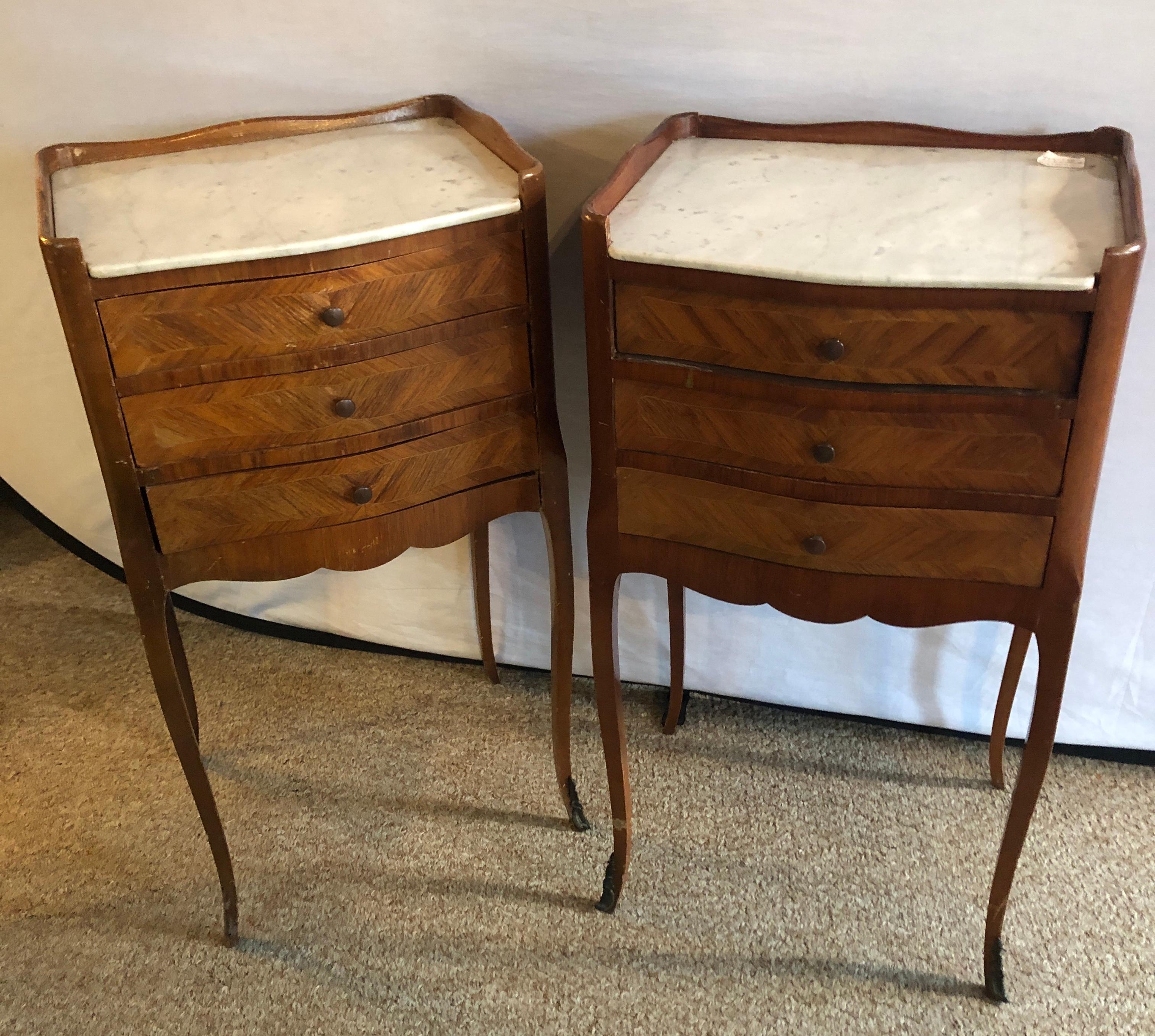 Pair of antique marble top 3-drawer stands / end tables or nightstands. These nicely formed French tables have white marble tops above three drawers with long lean tapering curved legs. Very stylish and simple.