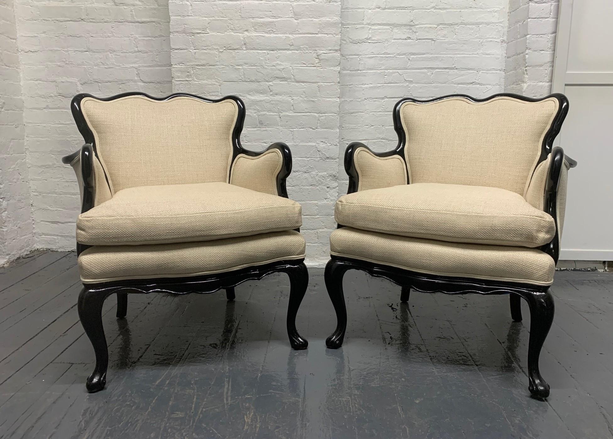 Pair of French antique style lounge chairs in linen. The chairs have black lacquered frames and loose cushioned seats.