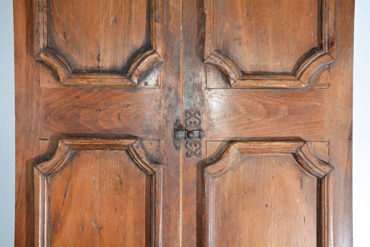 The pair of French antique doors or shutters is of wood and has one-over-one raised moldings. There is a metal latch and pairs of metal hinges. The backsides have structural framing.