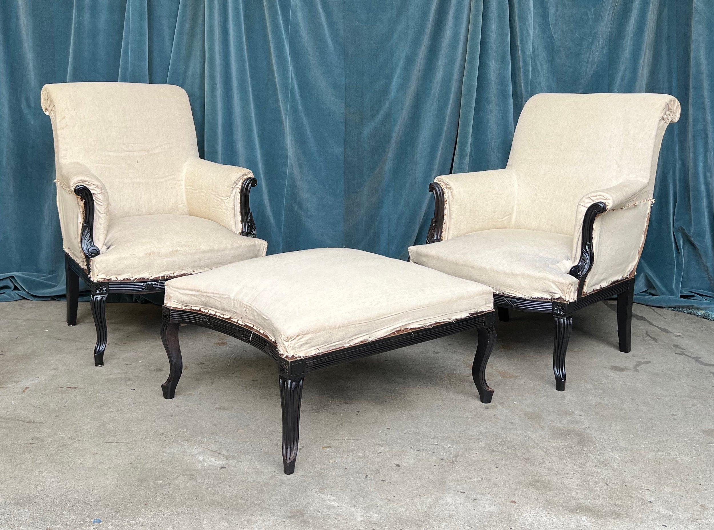 This striking trio of French armchairs and an ottoman from the 1920s is the embodiment of timeless elegance. The chairs and ottoman are a testament to fine artistry, with intricately carved wooden frameworks that have been freshly painted in a sleek