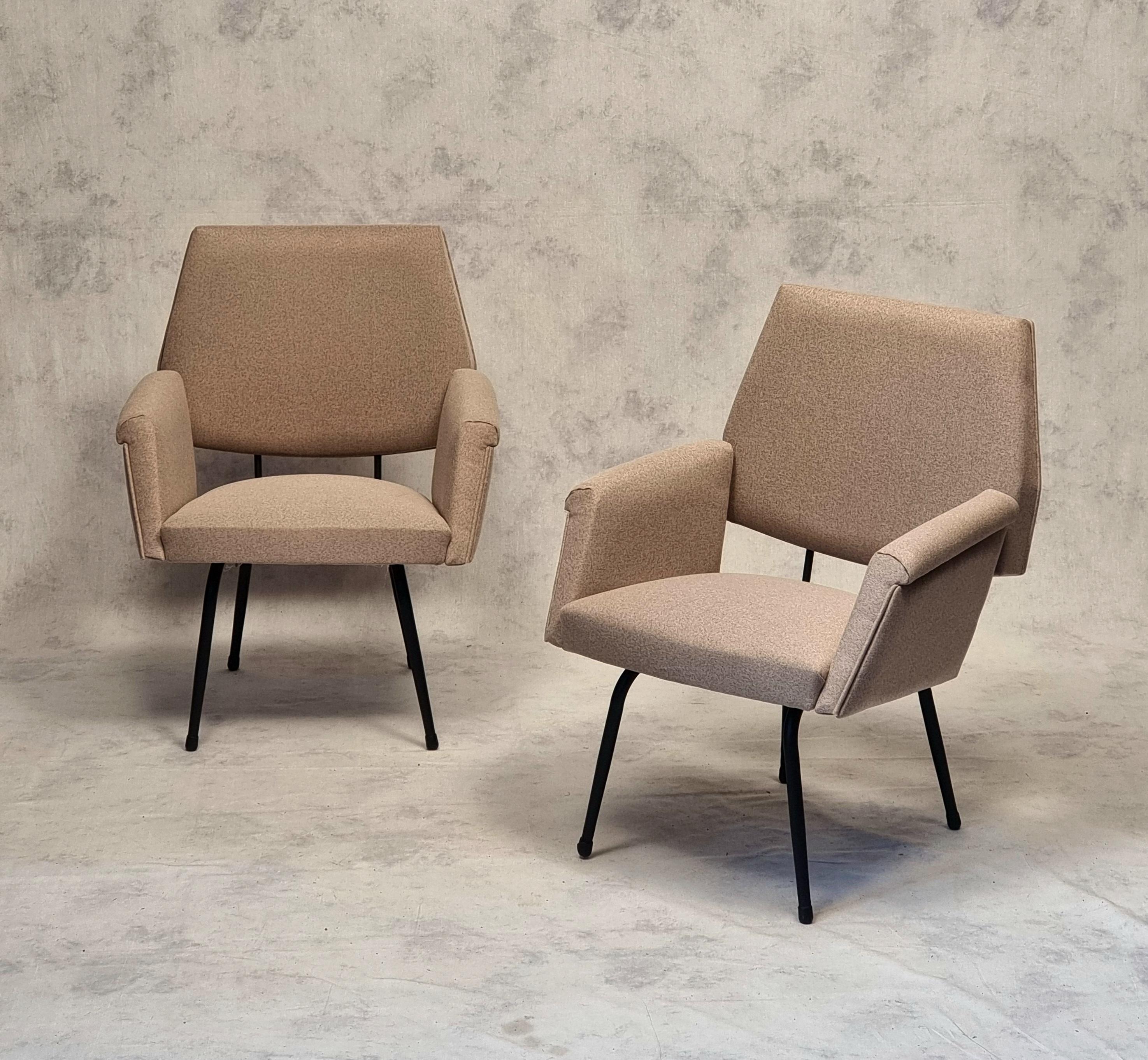 Pair of modernist armchairs from the 1950s. These armchairs of French origin are typical of the modernist movement. They are close to the work of Pierre Guariche in particular. They rest on a black lacquered tubular metal base. The armrests are