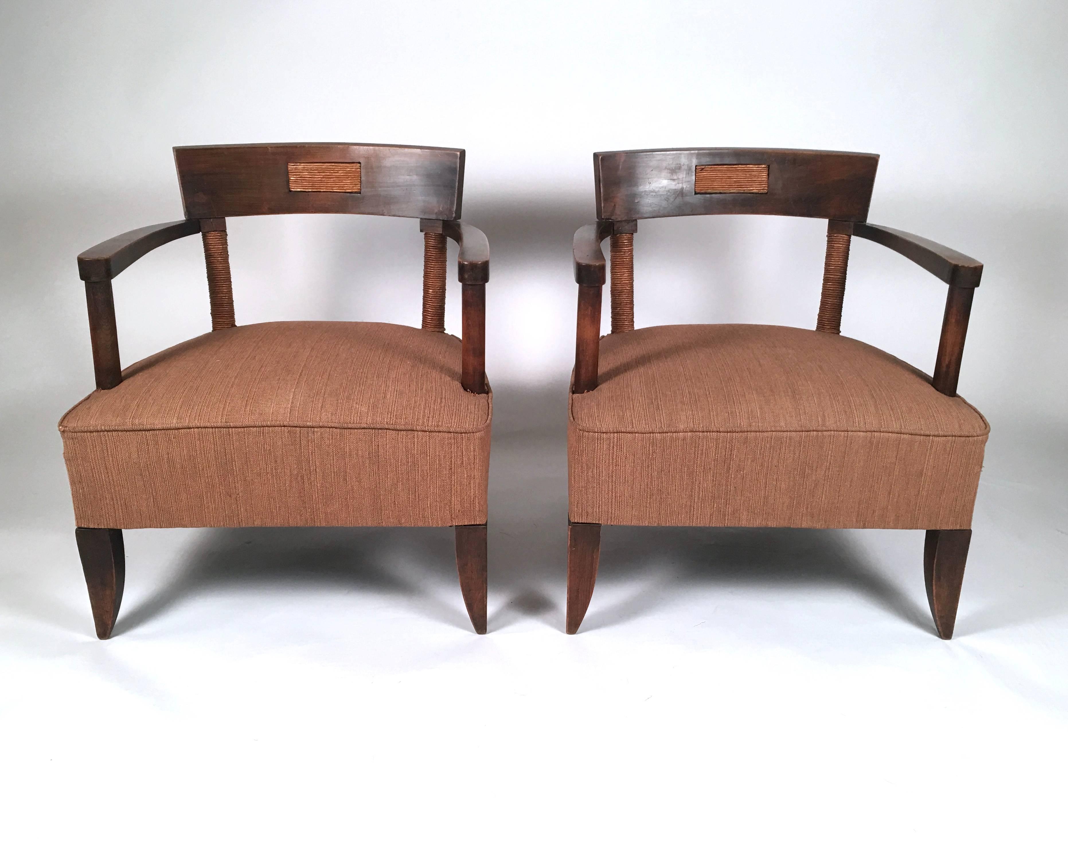 A pair of French Art Deco period African inspired armchairs in oak, the curved backs with inlaid paper cord rectangular panels in the back, with curved arm rests above two turned oak arm supports in the front and two round paper cord wrapped
