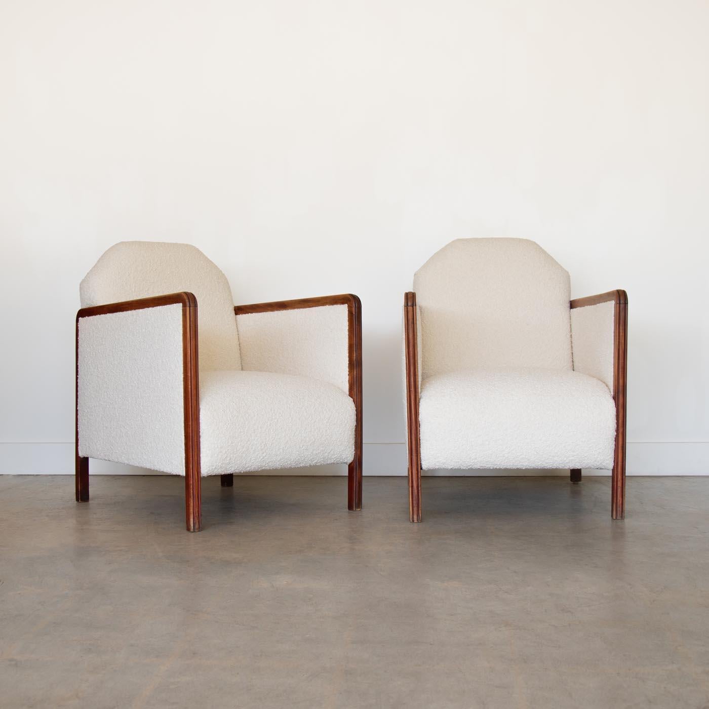Incredible pair of Art Deco arm chairs from France, 1930's. Beautiful angular wood frame with ribbed details on arms and newly upholstered in a creamy boucle fabric. A unique pair and stunning from all angles.