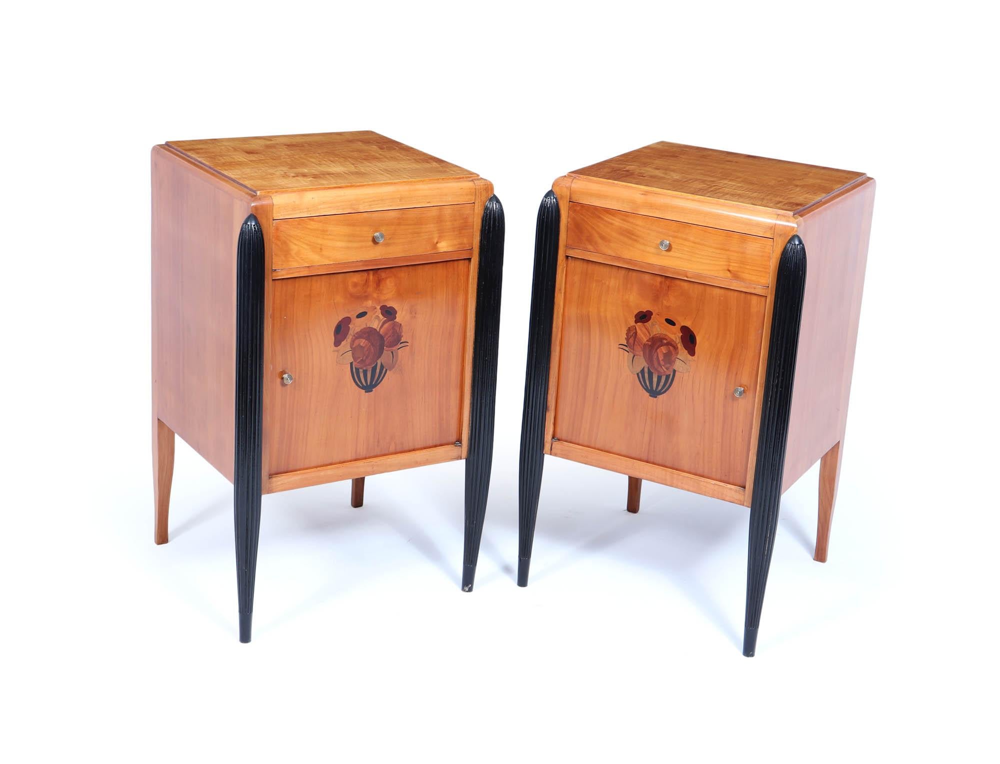 Art Deco Bedside Cabinets 
A Pair of French Art Deco bedside cabinets produced in the 1920’s using cherrywood, they have a single drawer with cupboard door below, all turned brass handles detailed flower motif to the door using ebony and other