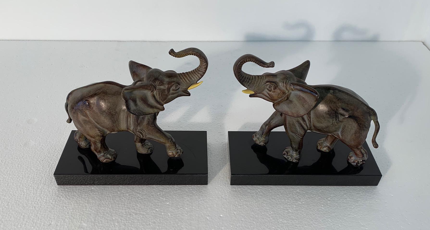 Pair of French Art Deco bookends representing two marching elephants.
Both bookends are made from bronze-colored patinated zamak, vividly detailed.
Both fixed on a black veined marble pedestal.
  