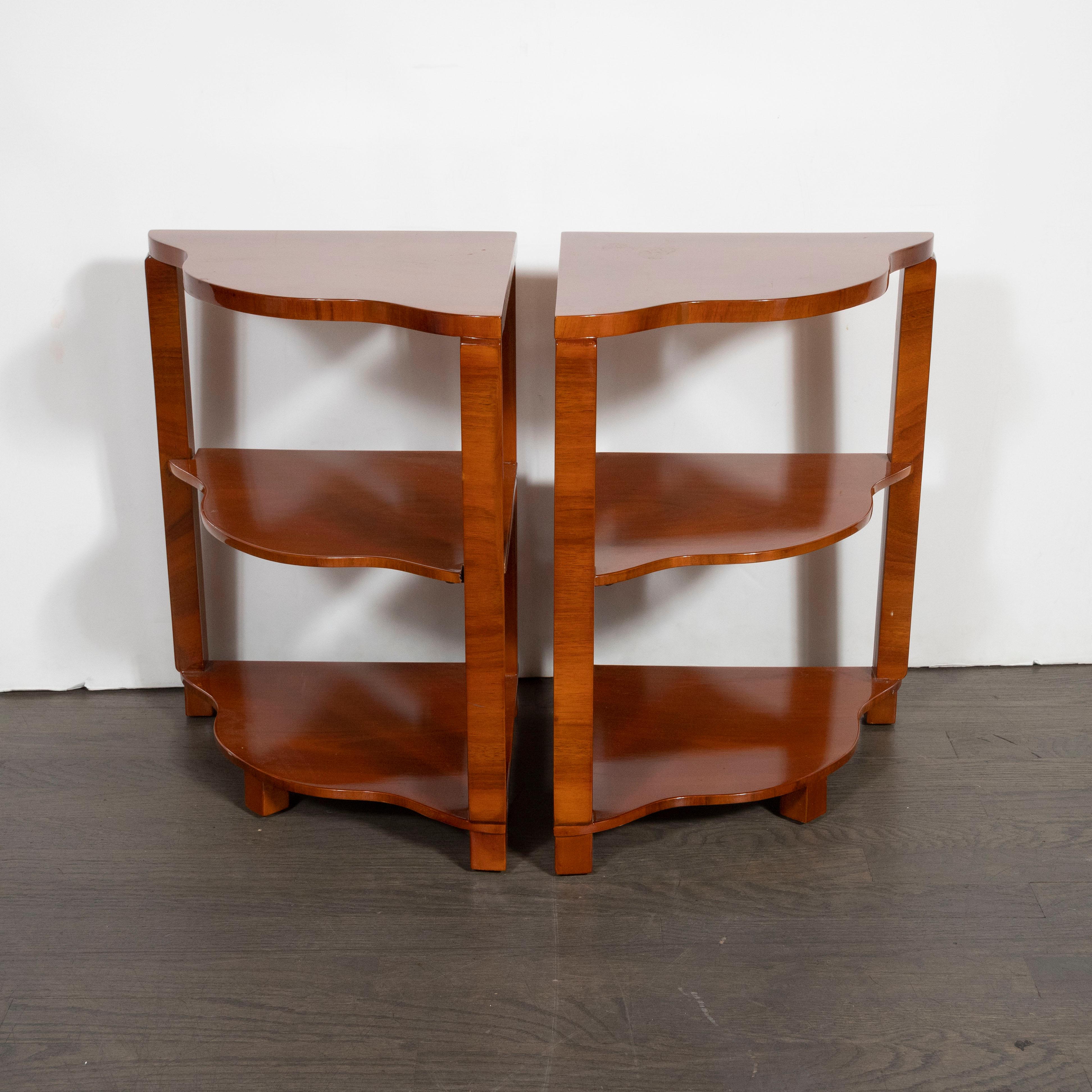 This elegant pair of Art Deco side/ end tables were realized in France, circa 1930. They feature two straight sides that adjoin at a right angle while one offers undulating curves, lending them the moniker of 