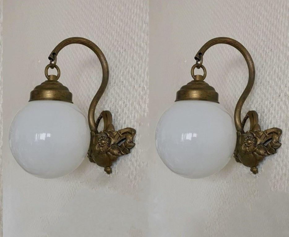 Pair of lovely bronzed brass wall sconces with opaline glass ball globes, for indoor and covered outdoor use, France, 1930-1939. Beautiful bronzed brass flower basket shape as wall mount.
Both sconces are in very good condition, beautiful patina to