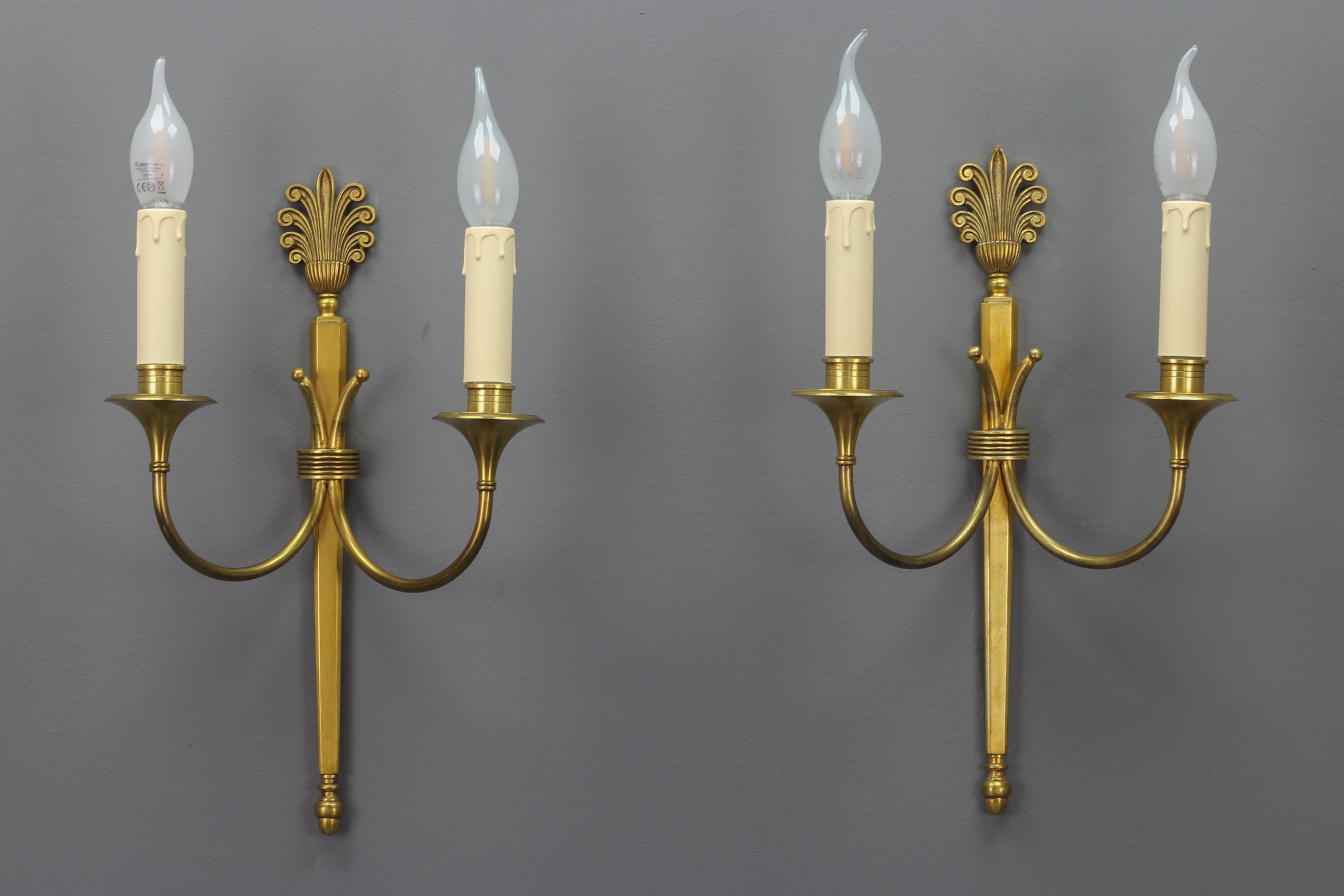 Pair of French Art Deco brass twin arm sconces from ca. 1930.
This elegant pair of brass sconces has a beautiful brass base with typical Art Deco-style decors. Each sconce has two arms each with a socket for E14 size light bulb. Numbered at the